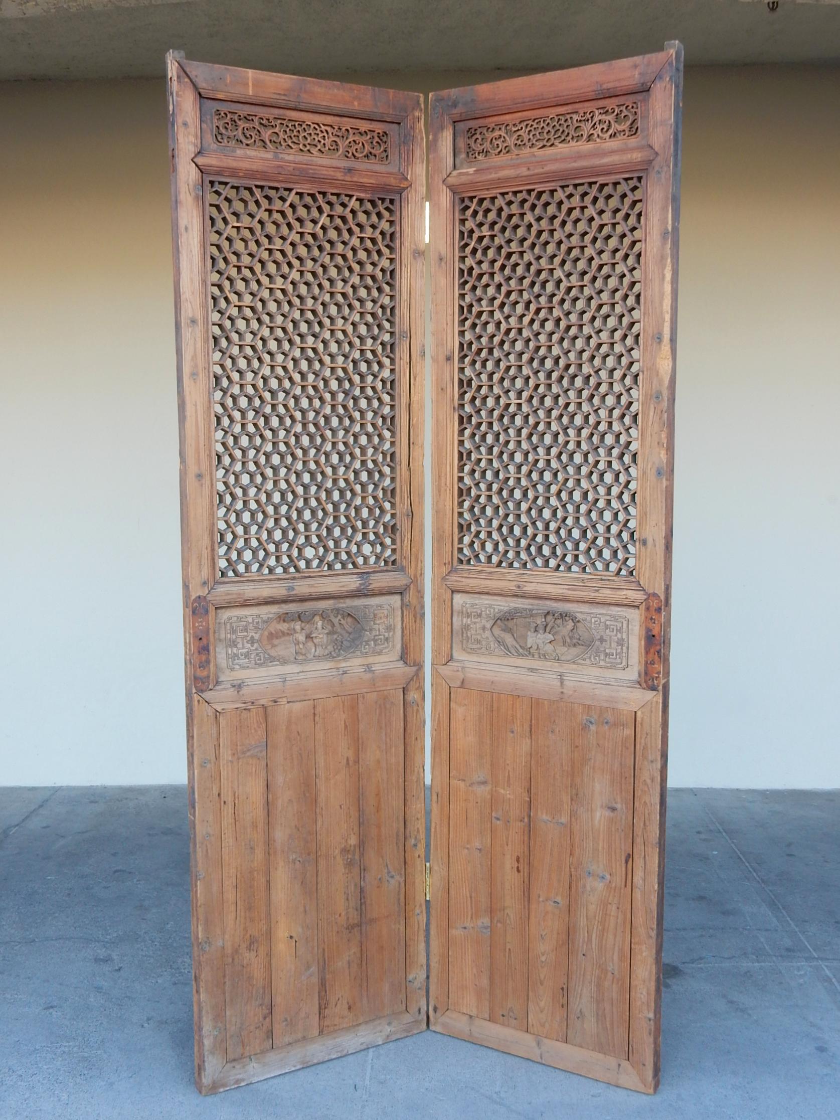 A pair of late 19th century China entry doors with
incredible honeycomb lattice-work. Floral scroll panels at top.
Carved figures across center. Center hinges were added to make them a
spectacular room divider screen.
Stands over 7-1/2 feet