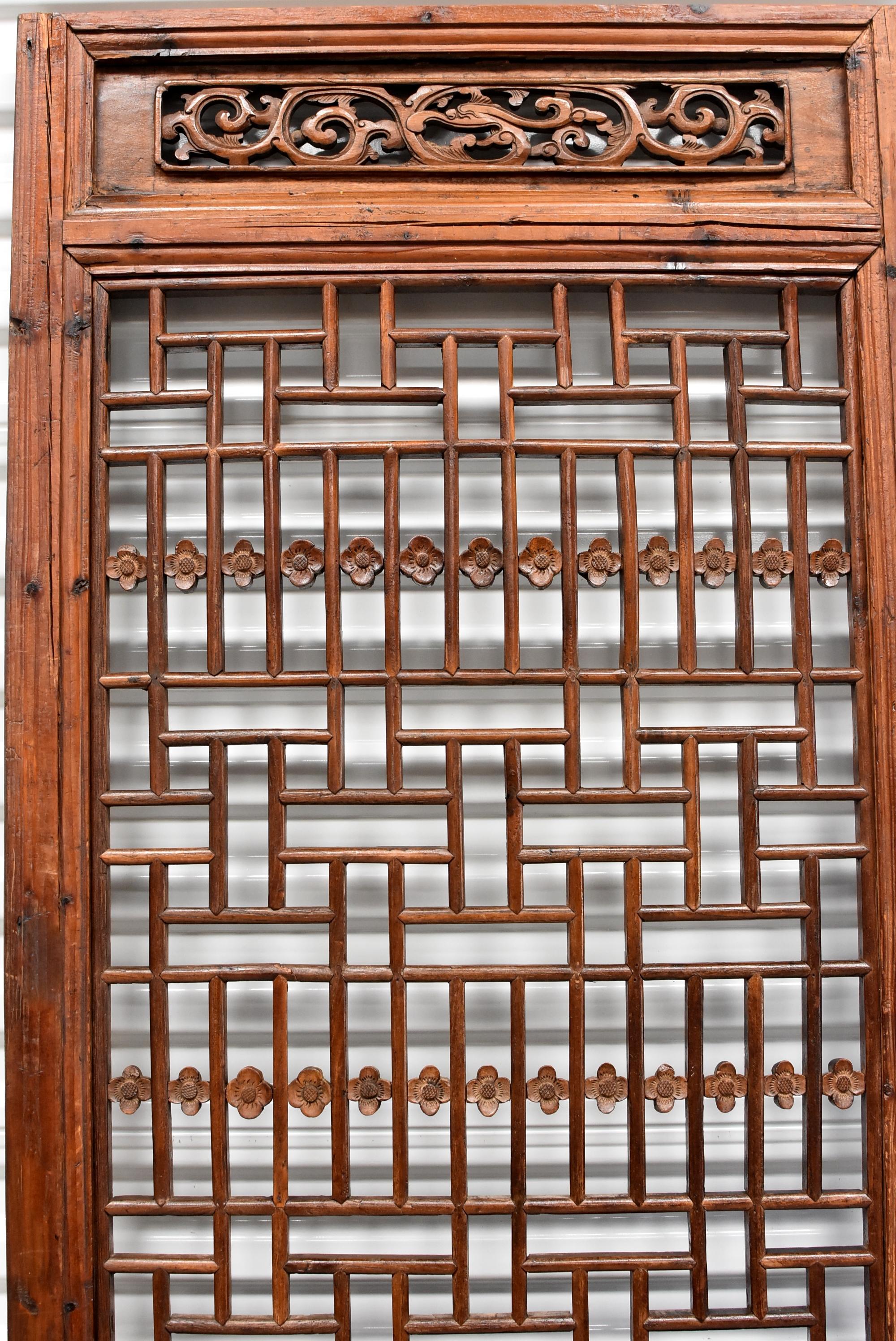 A beautiful single panel 19th century Chinese antique screen featuring carved plum blossoms with a geometric lattice design. The openwork is a connection of curved cuts of wood joined together by tenons and mortises. The top of the screen features a