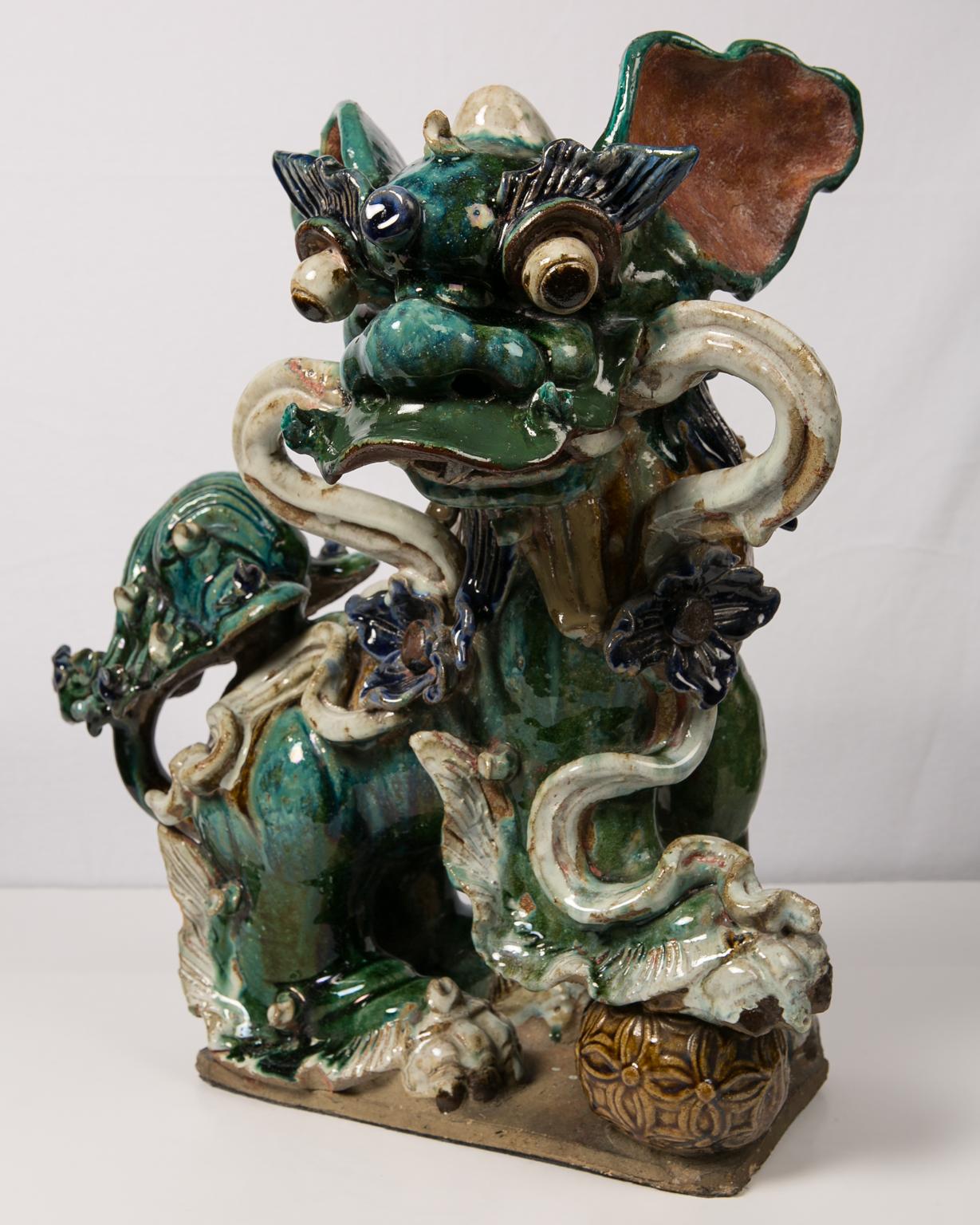 A pair of flamboyant Chinese lion dogs, also called Fu dogs, fully covered in rich glazes of green, turquoise, blue, brown, and white. This wonderful pair of sculptures is dated to the late-Qing period, from the early 20th century. Skilfully and