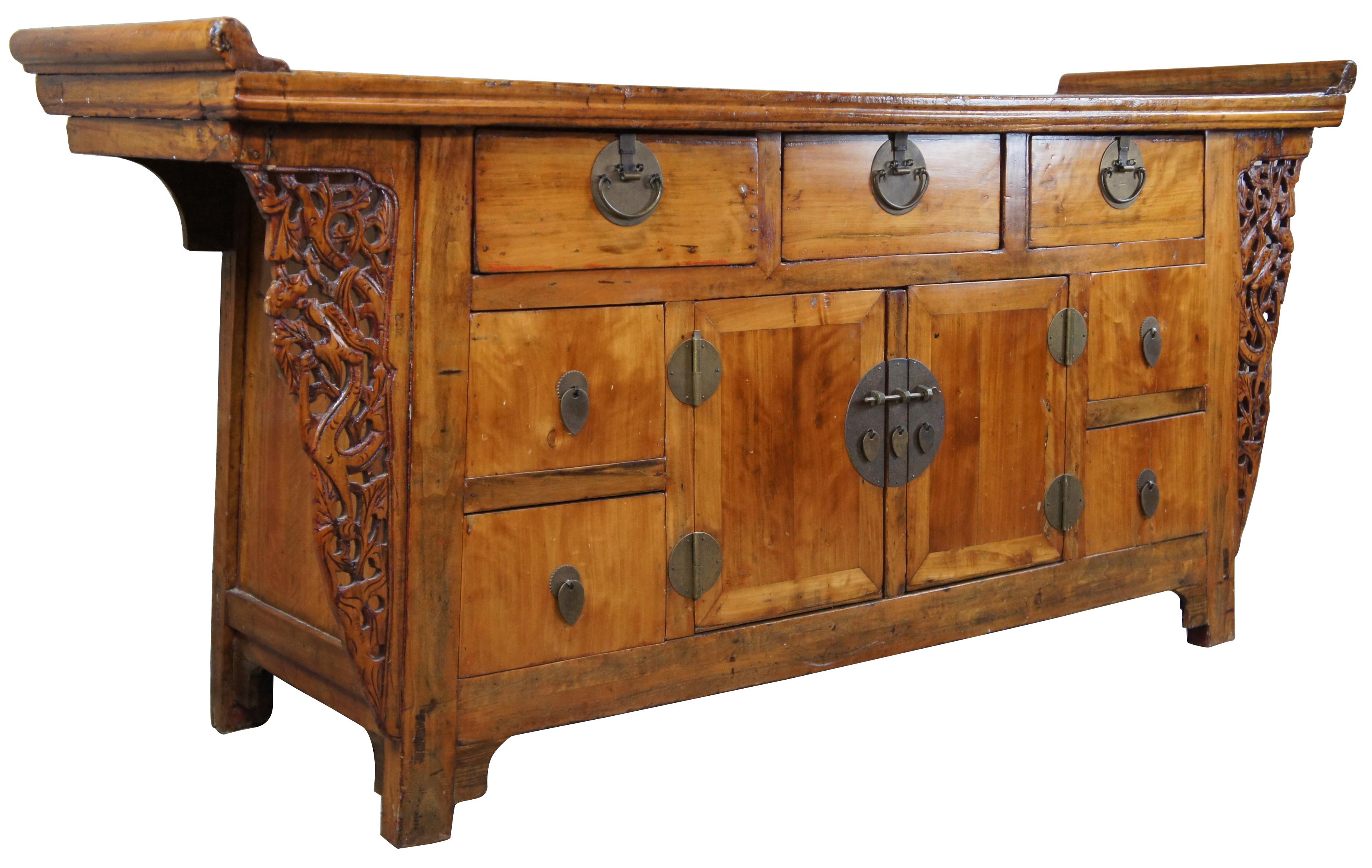 Mid-19th century Ming Dynasty inspired Huanghuali alter cabinet. Features a long plank top with flared accents over seven drawers and central cabinet. The decorative spandrels are elegantly carved with a pierced floral design. Great for an entryway,