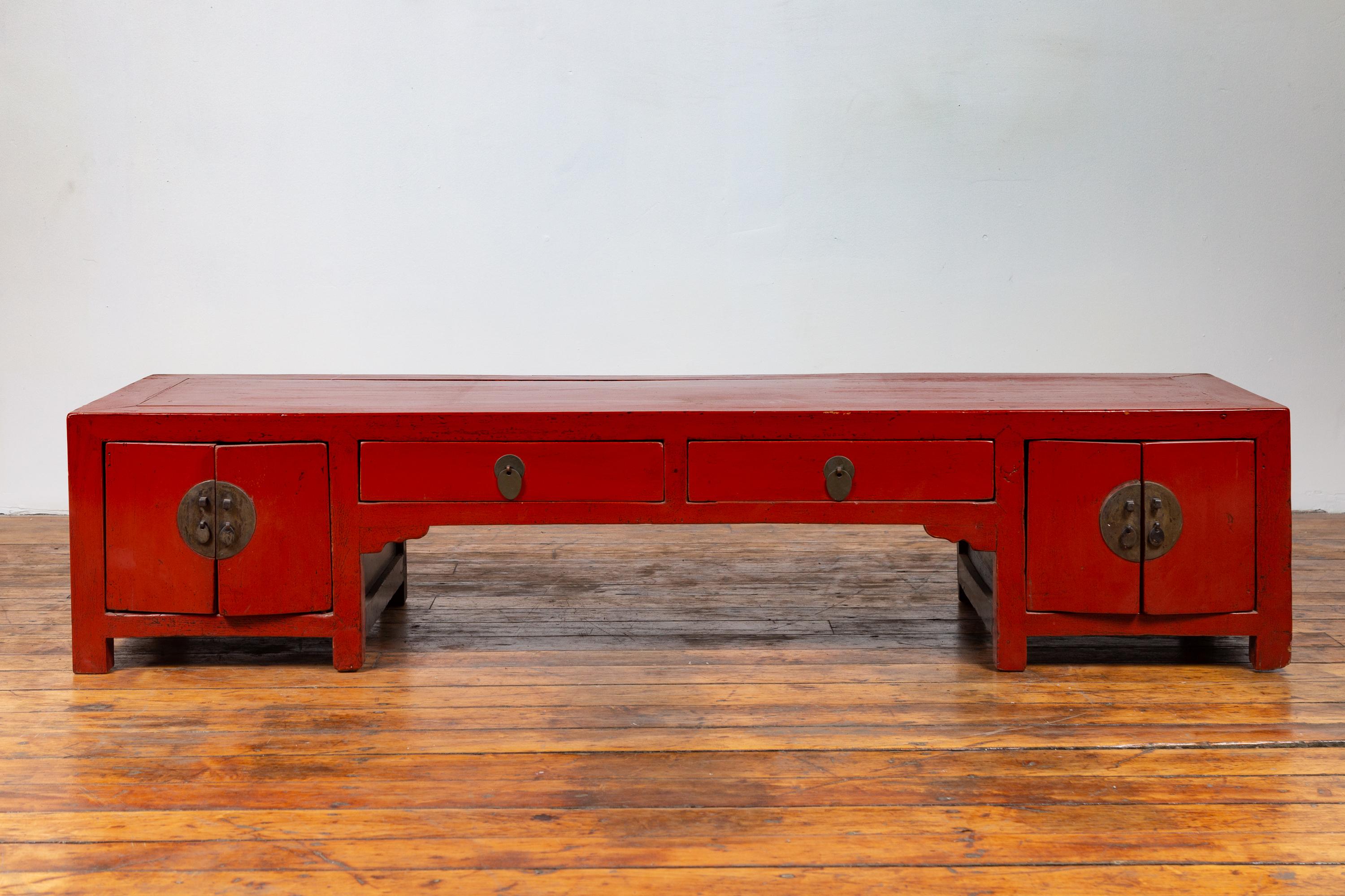 Antique Chinese Ming Dynasty style red lacquered low kang cabinet from the early 20th century, with drawers and doors. Born in China during the early years of the 20th century, this charming low kang cabinet features a red lacquered body