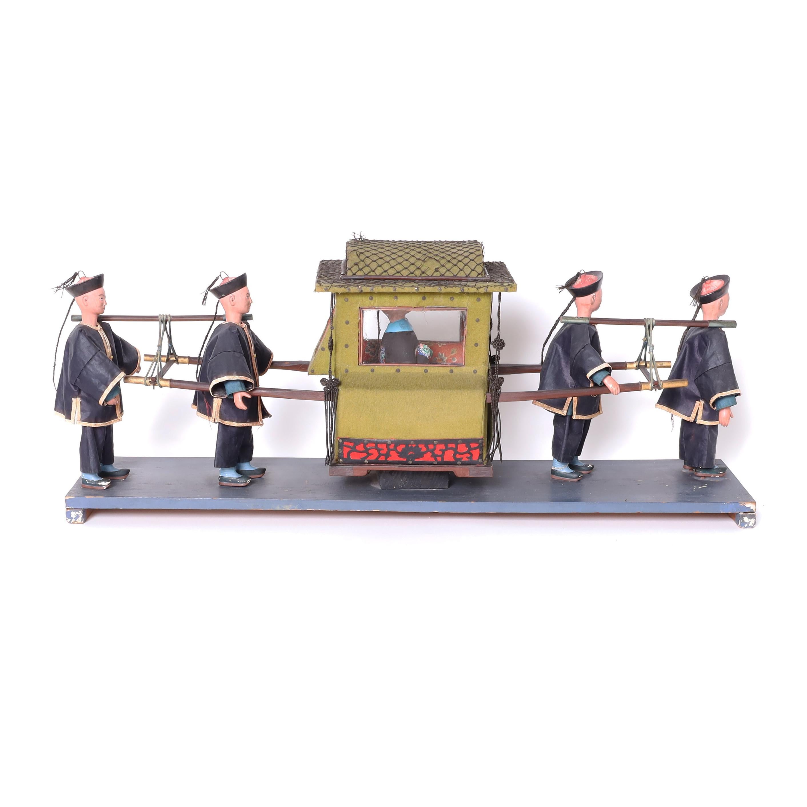 Rare et inhabituelle sculpture ou modèle chinois ancien représentant un souverain de Mandchourie porté sur un palanquin par quatre courtisans, le tout monté sur une plate-forme en bois.