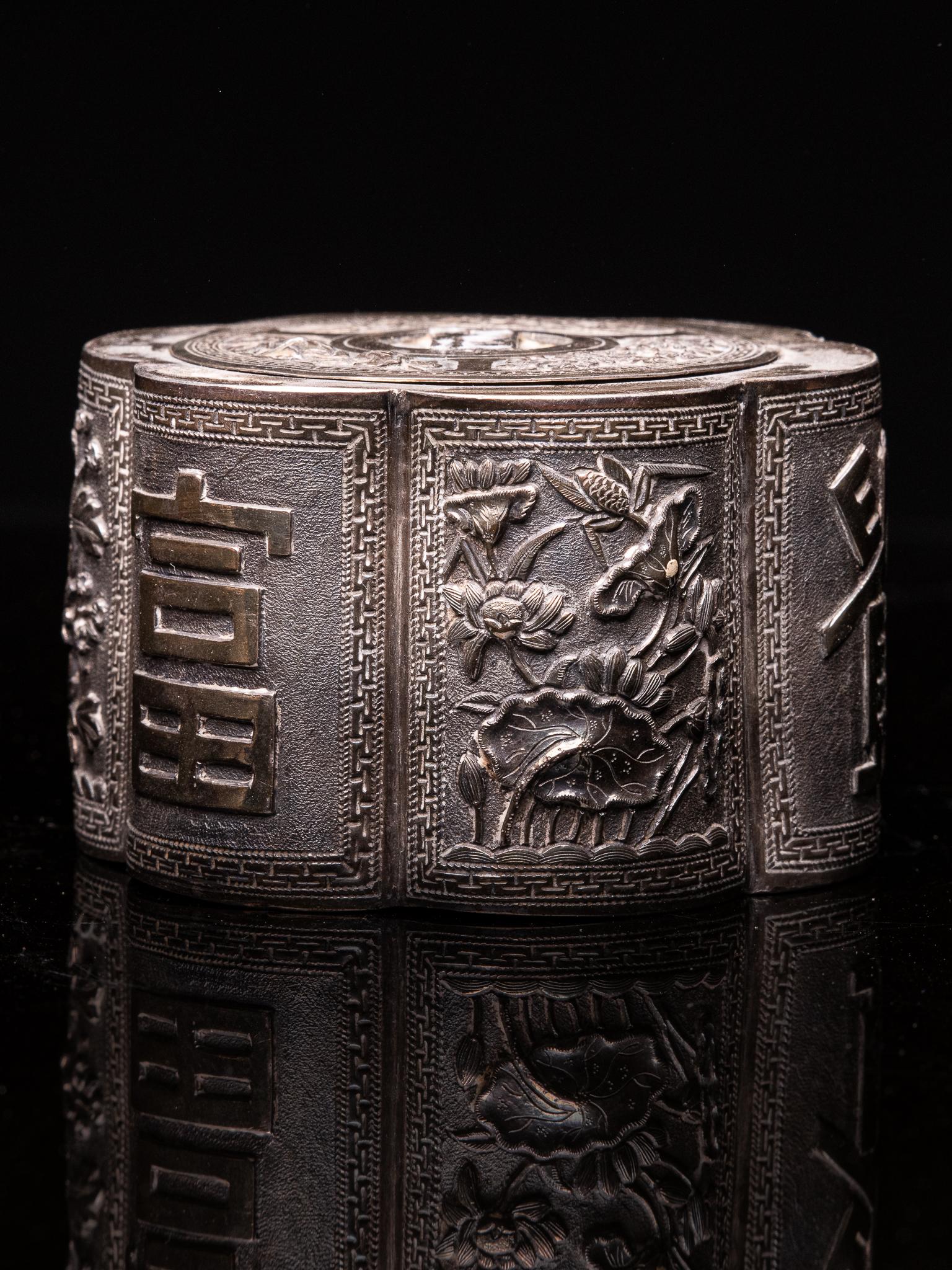 Beautiful opium box decorated with reliefs with ideograms (one of the two refers to wealth), a chrysanthemum (symbol of longevity) and foliage. This silver multi-lobed opium box is decorated with ideograms and flowers for luxury and longevity.