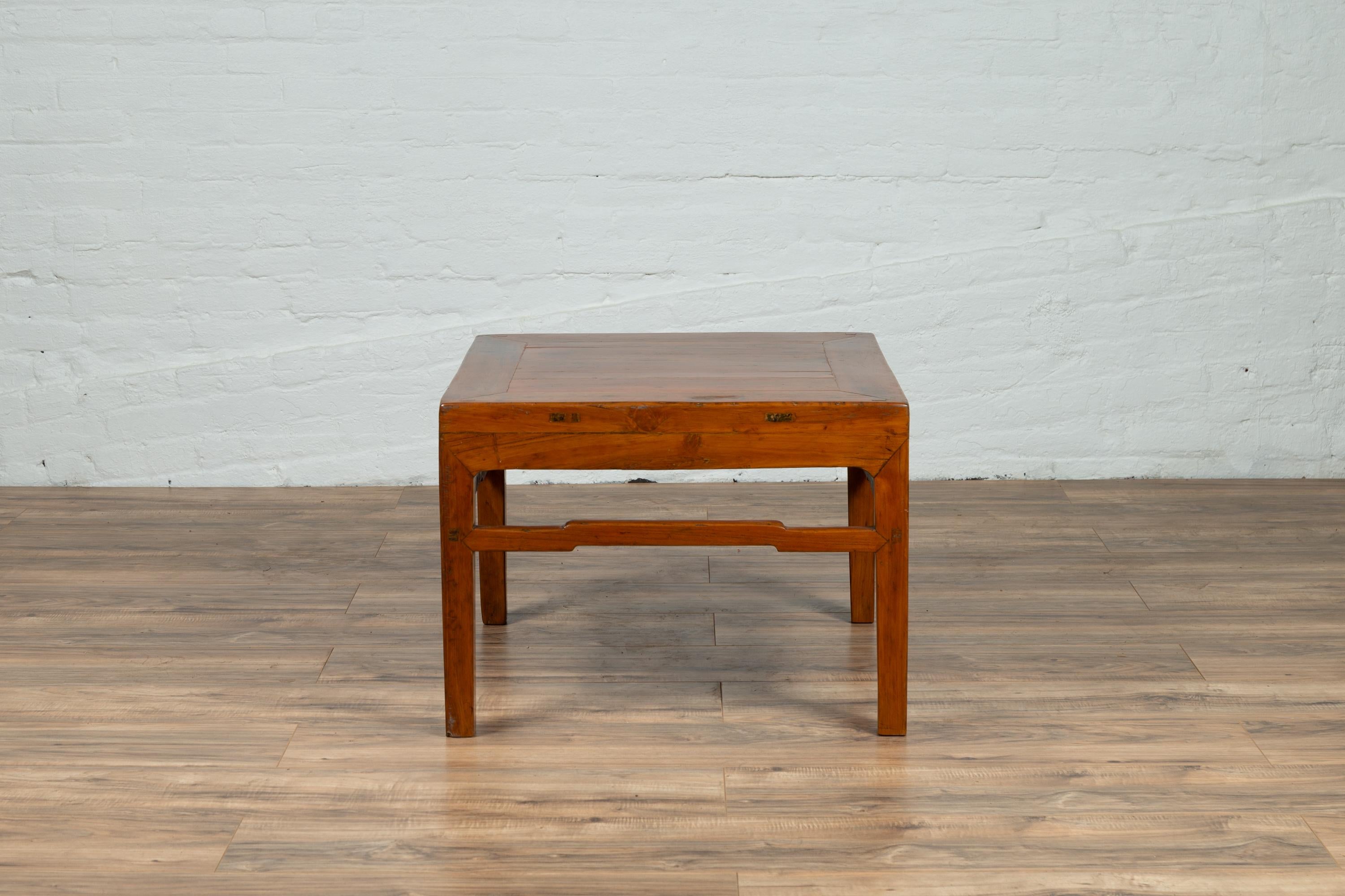 An antique Chinese natural wood side table from the early 20th century, with blond patina and humpback side stretchers. Born in China during the early years of the 20th century, this charming side table, originally conceived to be a stool, features