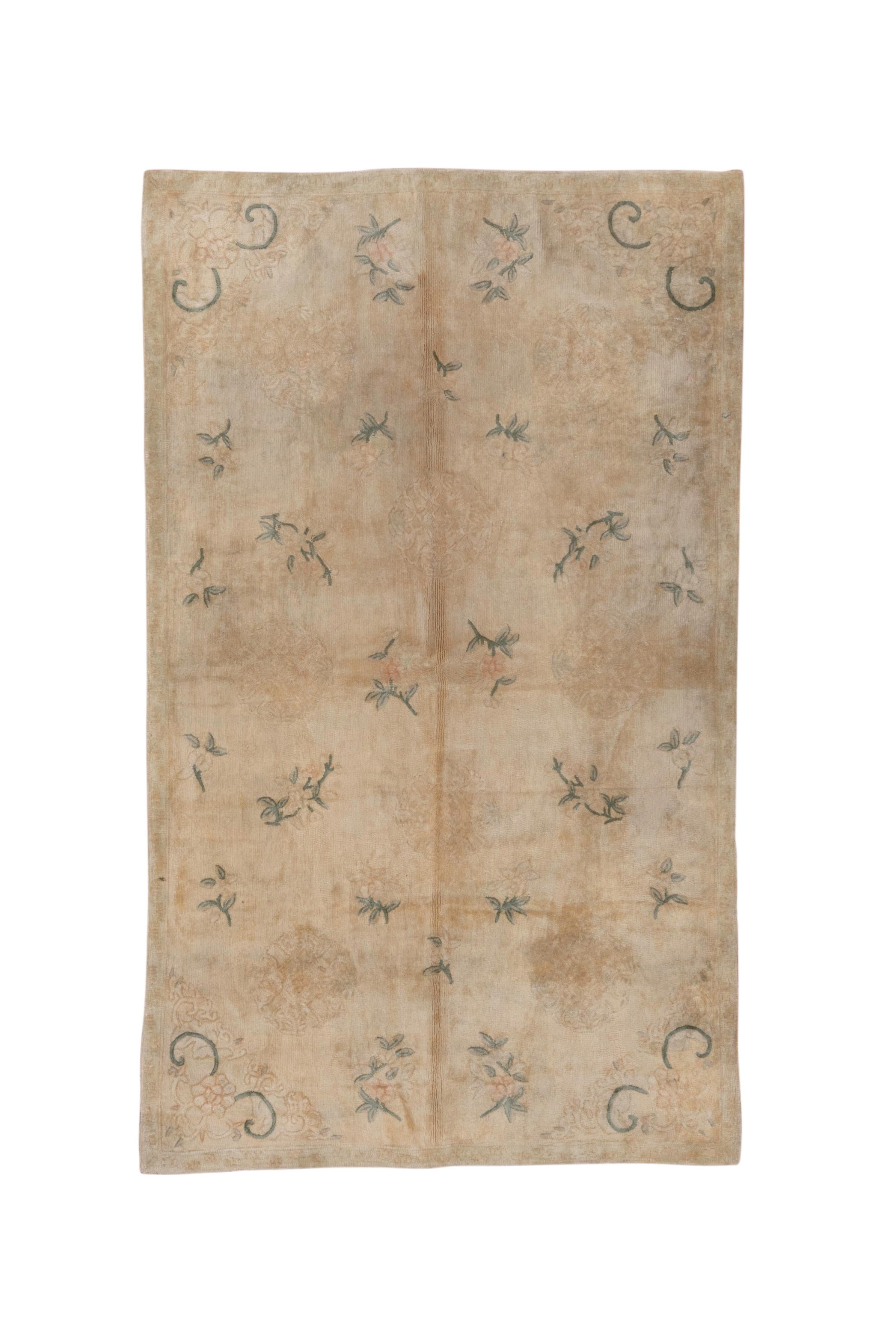 Dieses gut erhaltene Stück auf Baumwolle mit Flor, aber eher genadelt als geknüpft, zeigt ein beigefarbenes Feld mit einem vierfach symmetrischen, verstreuten Muster aus Blütensprays und Rosetten mit markanten Voluten in den Ecken. Schmale Ränder