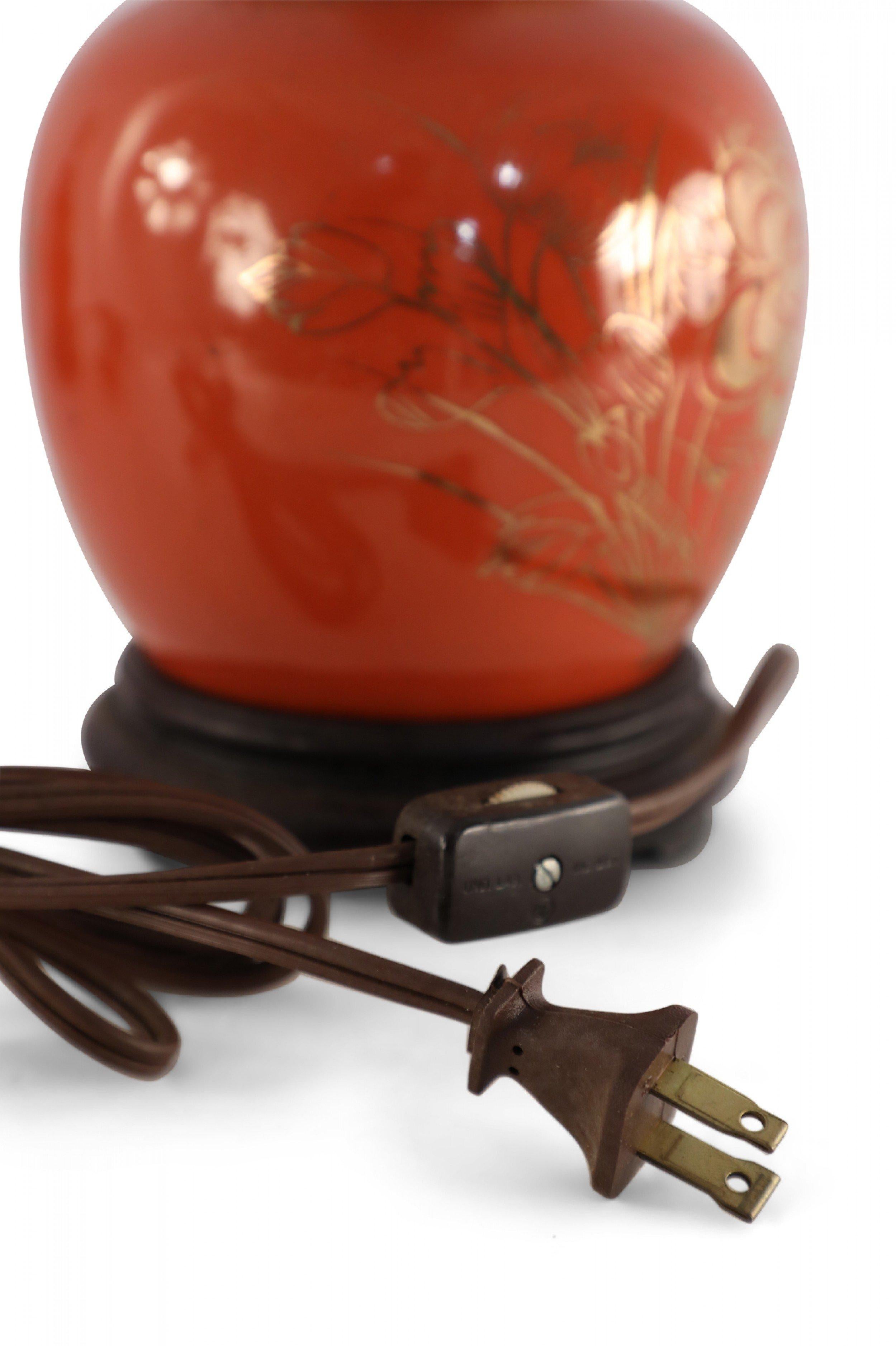 Lampe de table chinoise ancienne (début du 20e siècle) fabriquée à partir d'un vase rond en porcelaine orange lustrée avec un motif de bouquet floral doré, monté sur une base en bois brun et équipé de ferrures en laiton patiné.
 