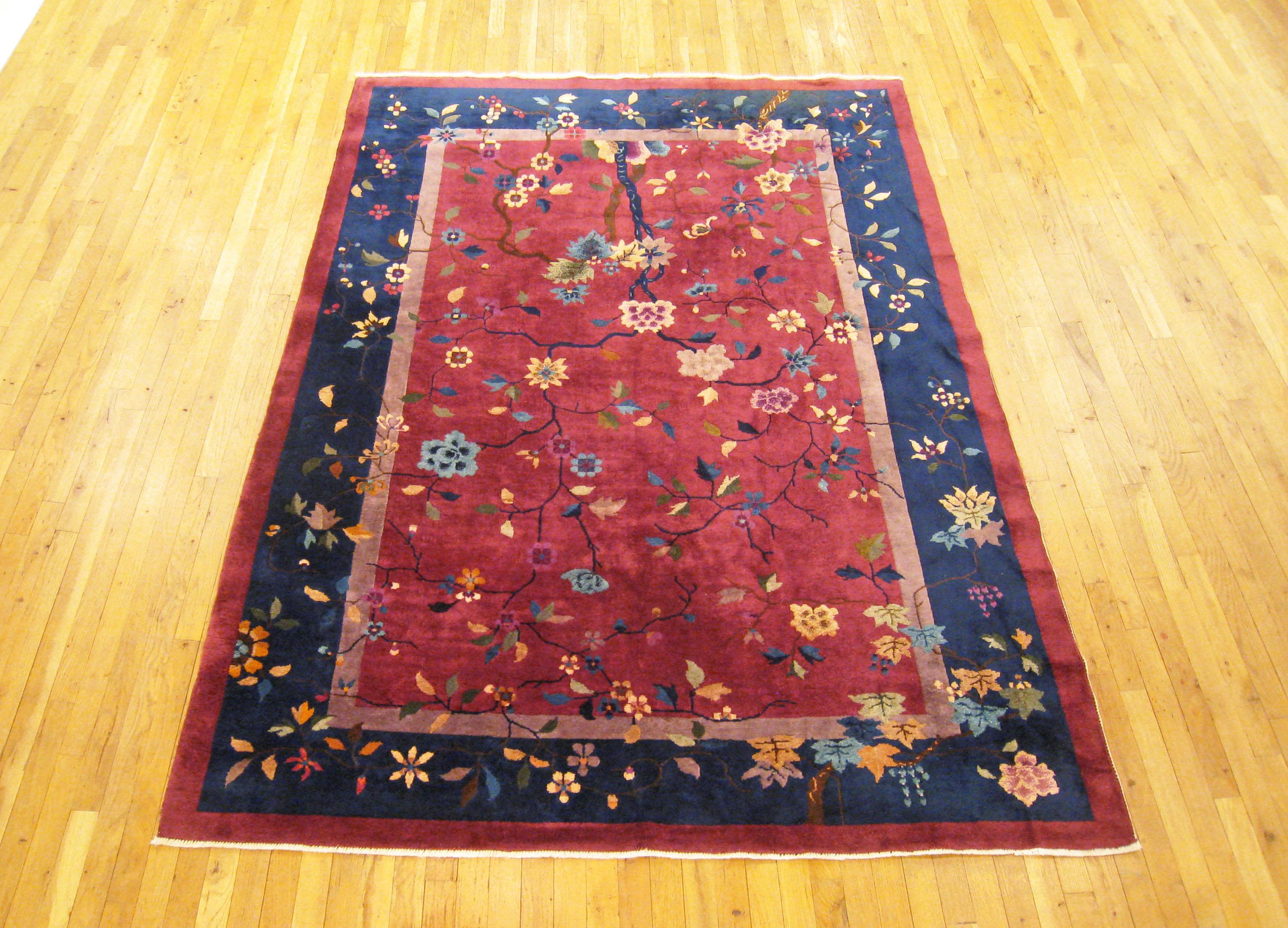 Antique Chinese rug, room size, circa 1920.

A one-of-a-kind antique Chinese oriental carpet, hand-knotted with medium thickness wool pile. This beautiful hand-knotted rug features floral elements allover a soft red field, with a blue outer border