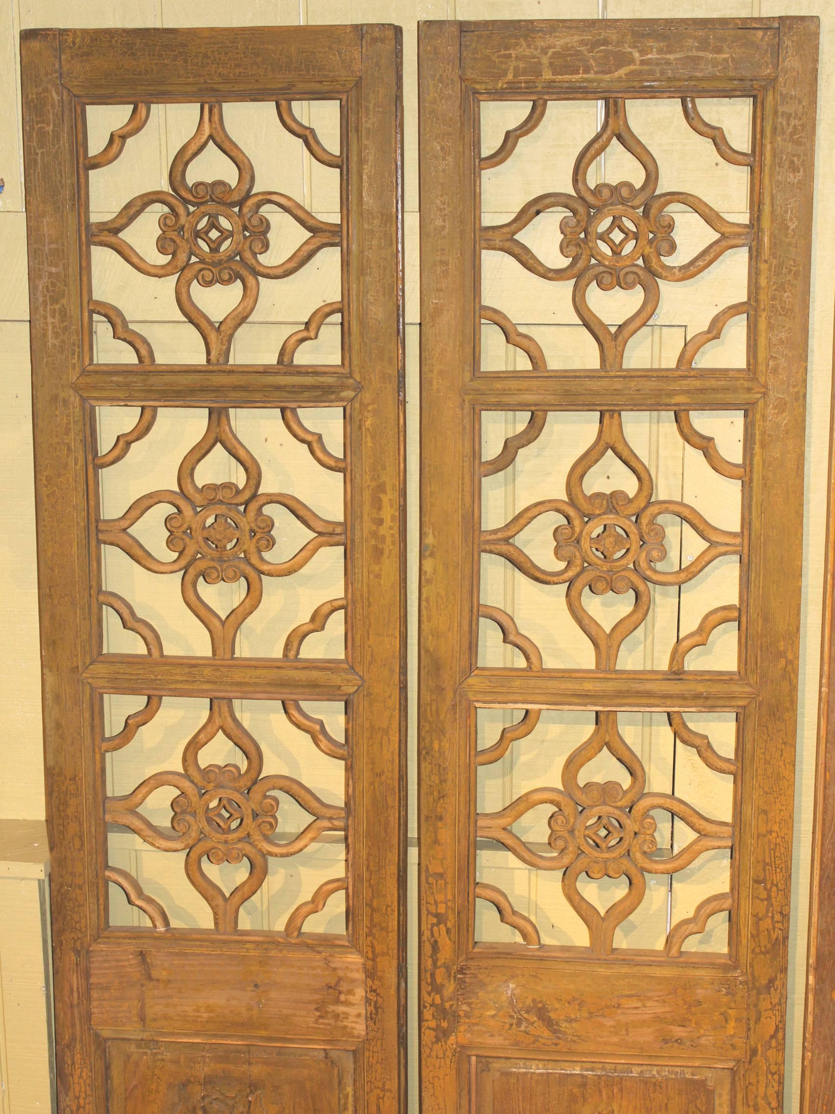Four splendid carved panels of an antique Chinese wooden screen with the open four lucky keys carved pattern in the top panels, circa 1916, in old yellow or gold paint on one side, old blue paint on verso, with carved birds, possibly peacocks, and