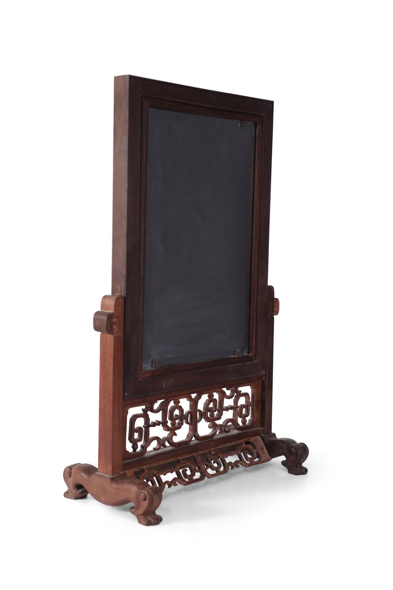 Miroir de courtoisie sur pied en bois sculpté, avec une surface réfléchissante d'un côté, et une plaque en porcelaine peinte à la main au revers, représentant une scène pastorale avec des personnages dans le coin supérieur droit.
     
