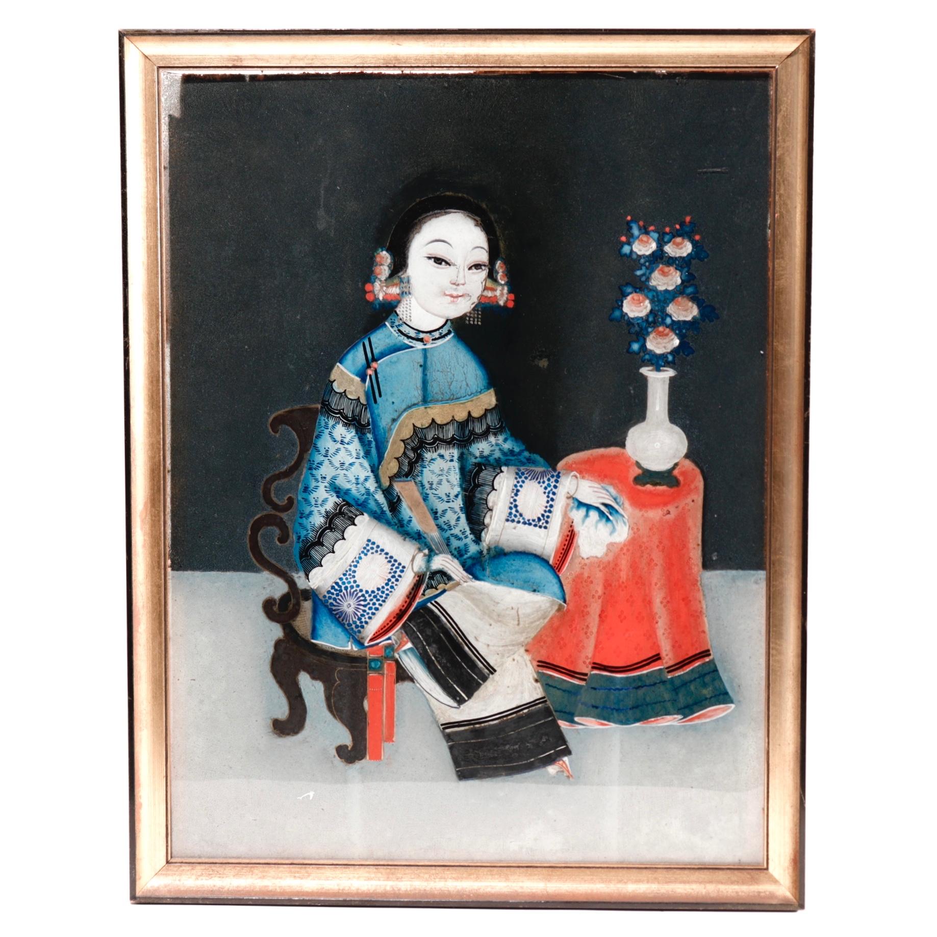 Chinese Pair of Reverse Glass Paintings, each depicting a young lady seated at a table, one with flute in hand, the other with a fan, each seated on a chair with a red cover cloth and in the background a covered table bearing a flower vase, the