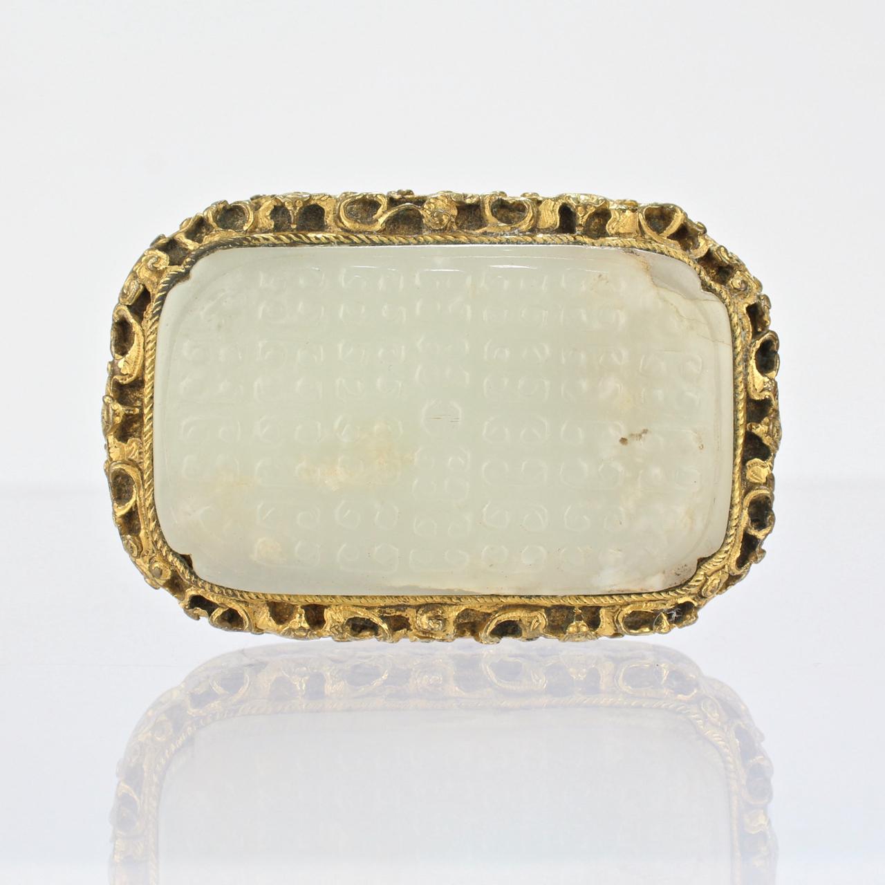 A fine antique Chinese gilt bronze belt buckle set with a rectangular carved jade plaque.

The ornate frame appears to be fire gilt. The pale celadon color jade is carved with an archaic style pattern.

Dating to the early 19th or possibly 18th