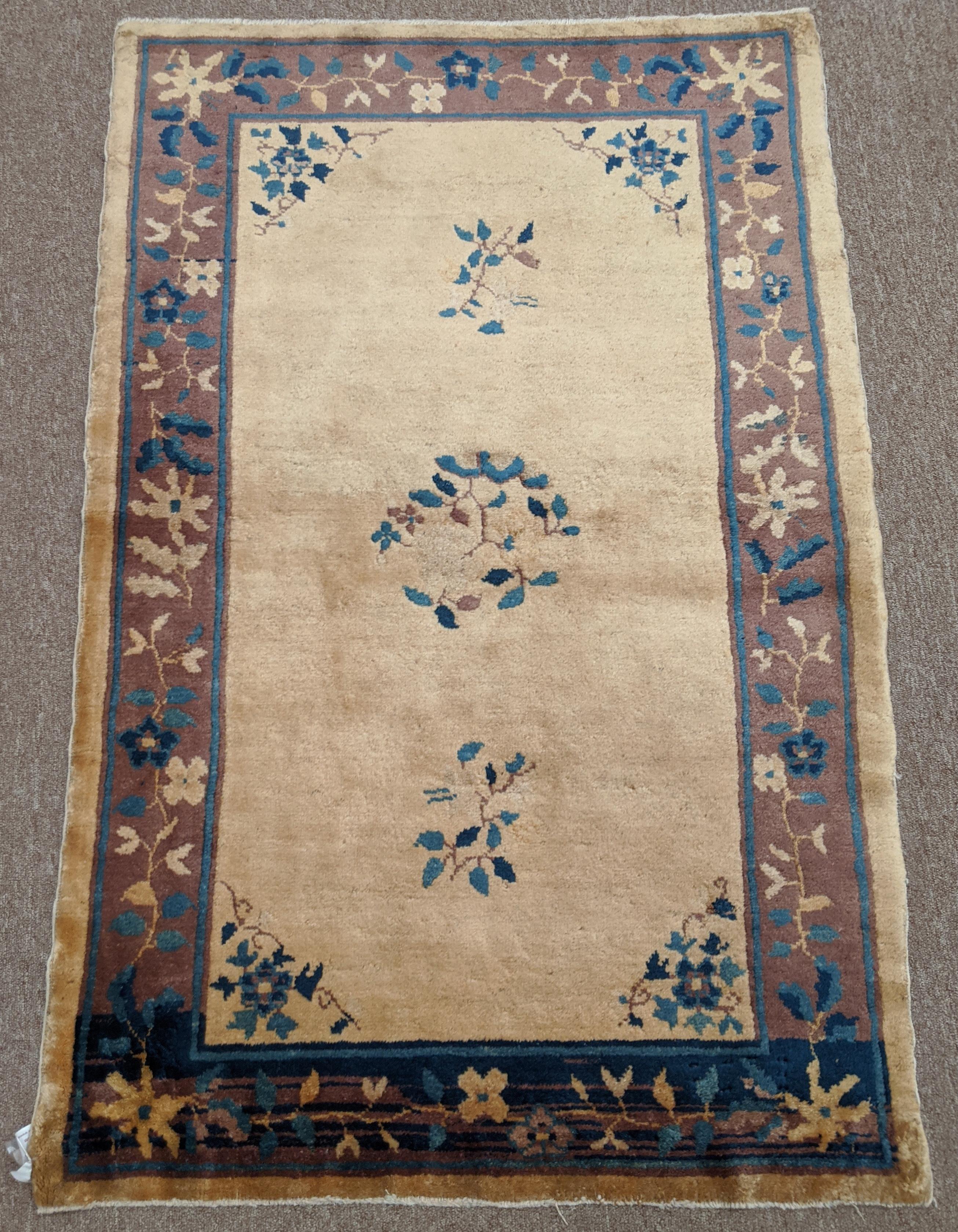 This is an antique Chinese rug from Peking. These rugs are noted for their soft silky like wool and their traditional oriental motif. The ivory field is encased in a taupe colored border with an interesting series of abrashes at one end. This rug is
