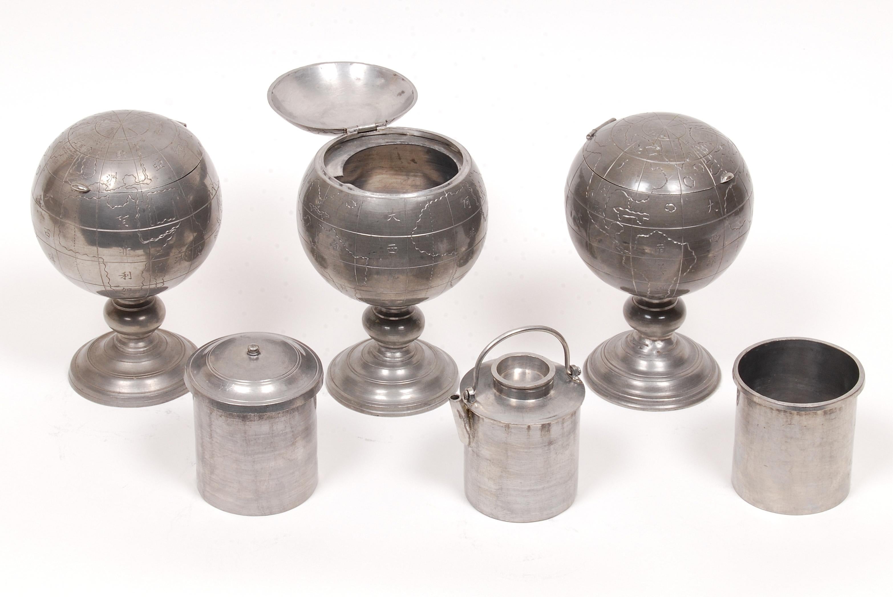 A set of three Chinese tea caddies in the form of a world globes. Includes engraved longitudes, latitudes, continents and oceans identified with Chinese characters. The pewter globe has a hinged lid and is set on a stepped circular base. The