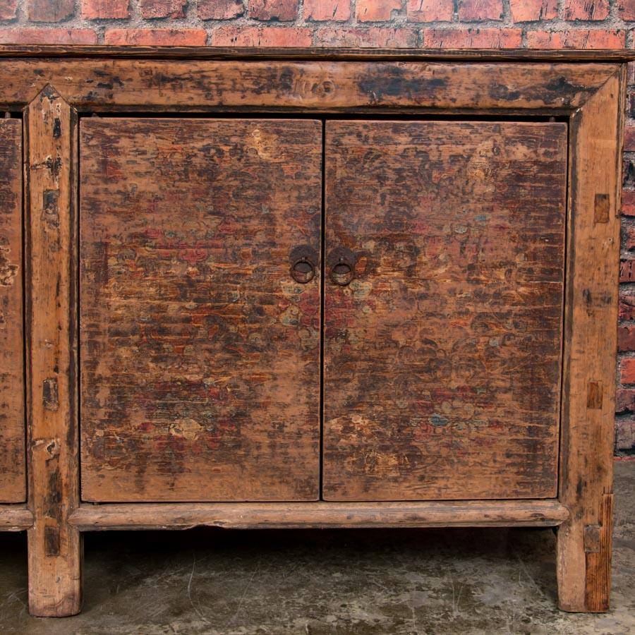 The visual appeal of this stunning antique Chinese sideboard is a combination of elements, the painted design and the warm matte finish. Most of the original brown lacquered finish has been worn away or sanded to reveal the pine wood below, giving