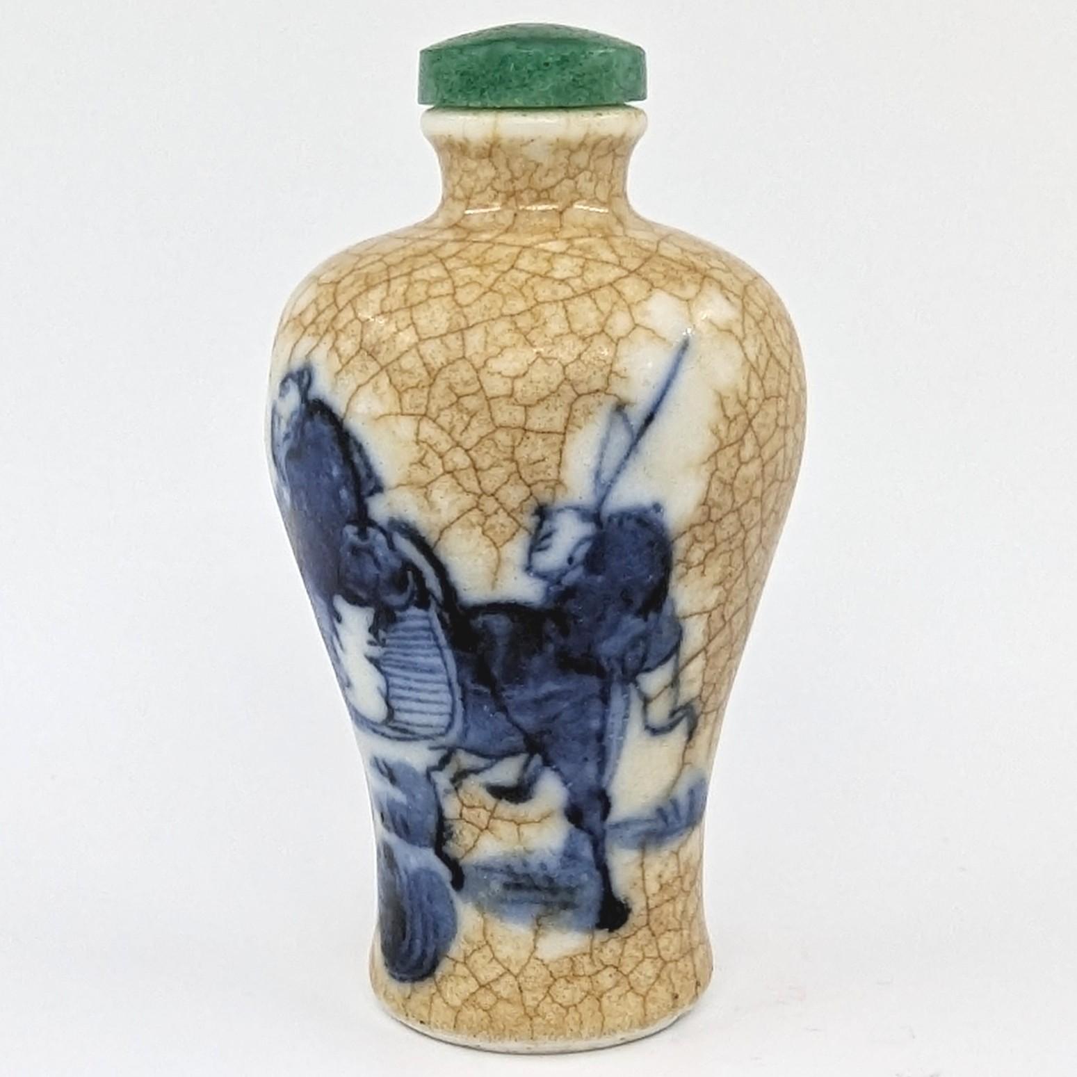 Antique Chinese porcelain snuff bottle in meiping form, painted in underglaze blue and white of a winter scene with a donkey riding scholar and an attendant, on crackle glaze including within the footring, with a green jade stopper and wooden