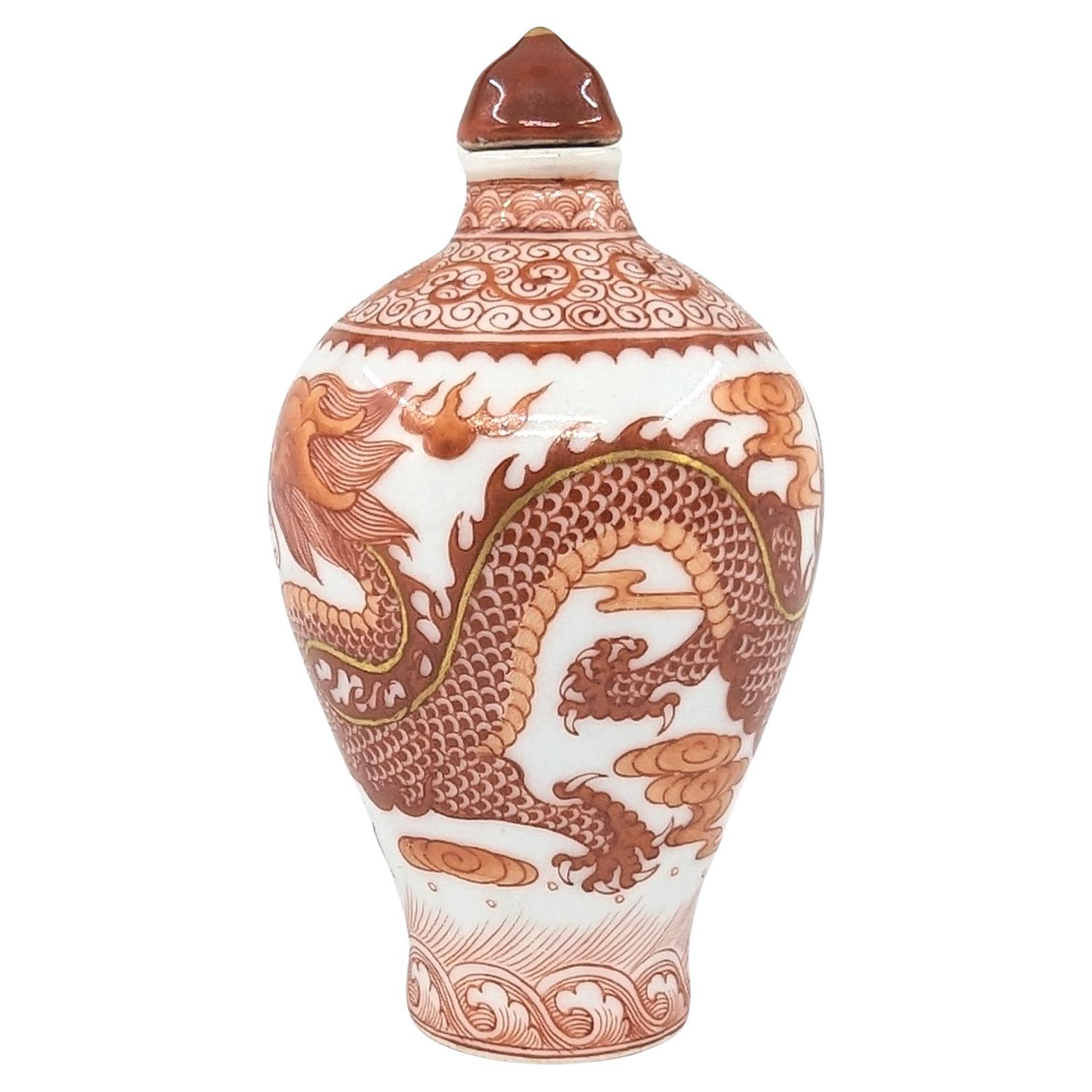 Antique Chinese porcelain snuff bottle in baluster form, finely painted in iron red, of a scaly five clawed dragon among clouds and flames, with spine decorated in polished 