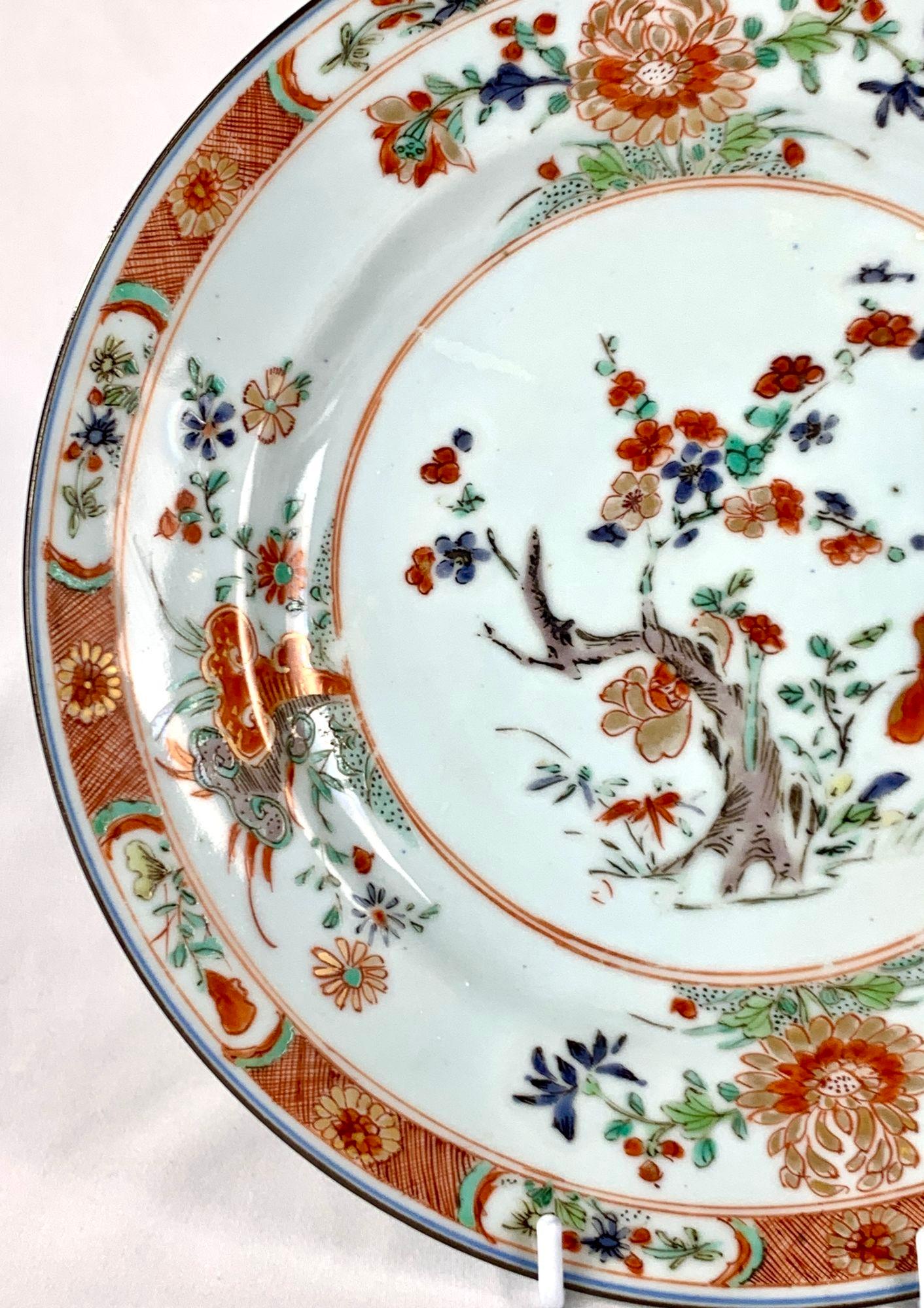 This antique Chinese export porcelain dish was hand-painted in the mid-18th century in the Qianlong Era.
It features a blossoming plum tree adorned with orange, blue, and gold flowers and green leaves.
The dish's wide border is embellished with four