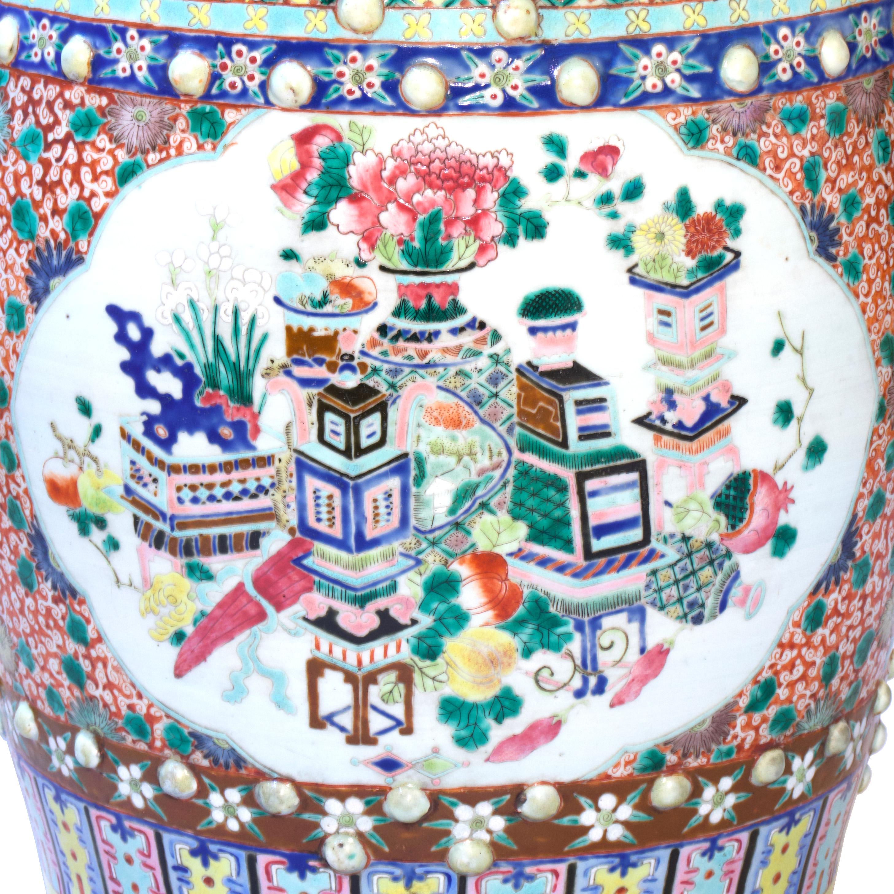 The barrel drum form with coin cutouts on top and overlapping on opposing sides has raised bosses in the enameled border bands top and bottom. Glazed overall with various multicolored polychrome enamels with two large cartouches on the sides