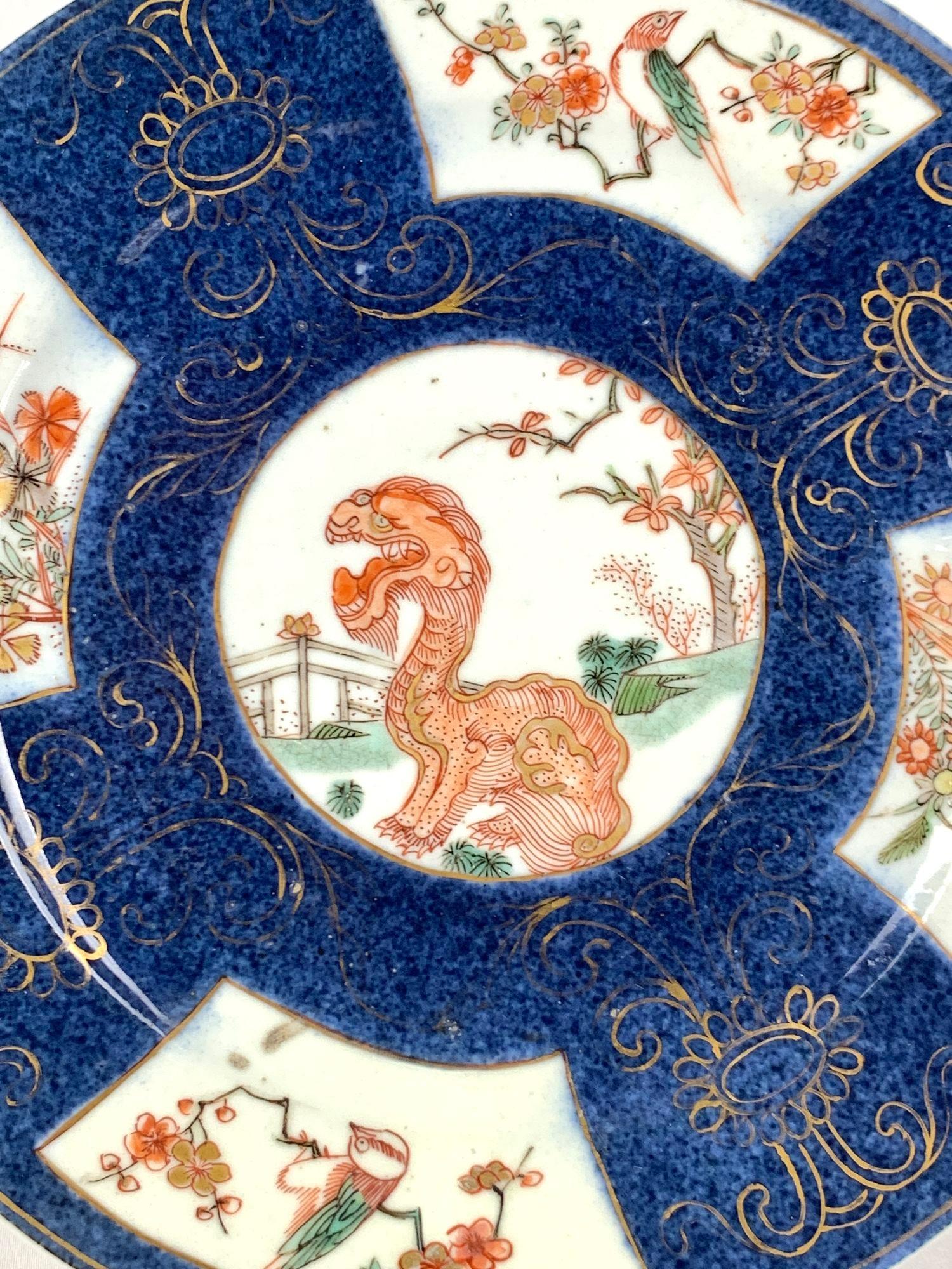 This exquisite Chinese porcelain powder-blue dish was hand-painted in the 18th century during the Qianlong Era, circa 1760.
The center is painted in famille verte enamels.
It features a fierce *Kylin in a traditional fenced garden with a flowering