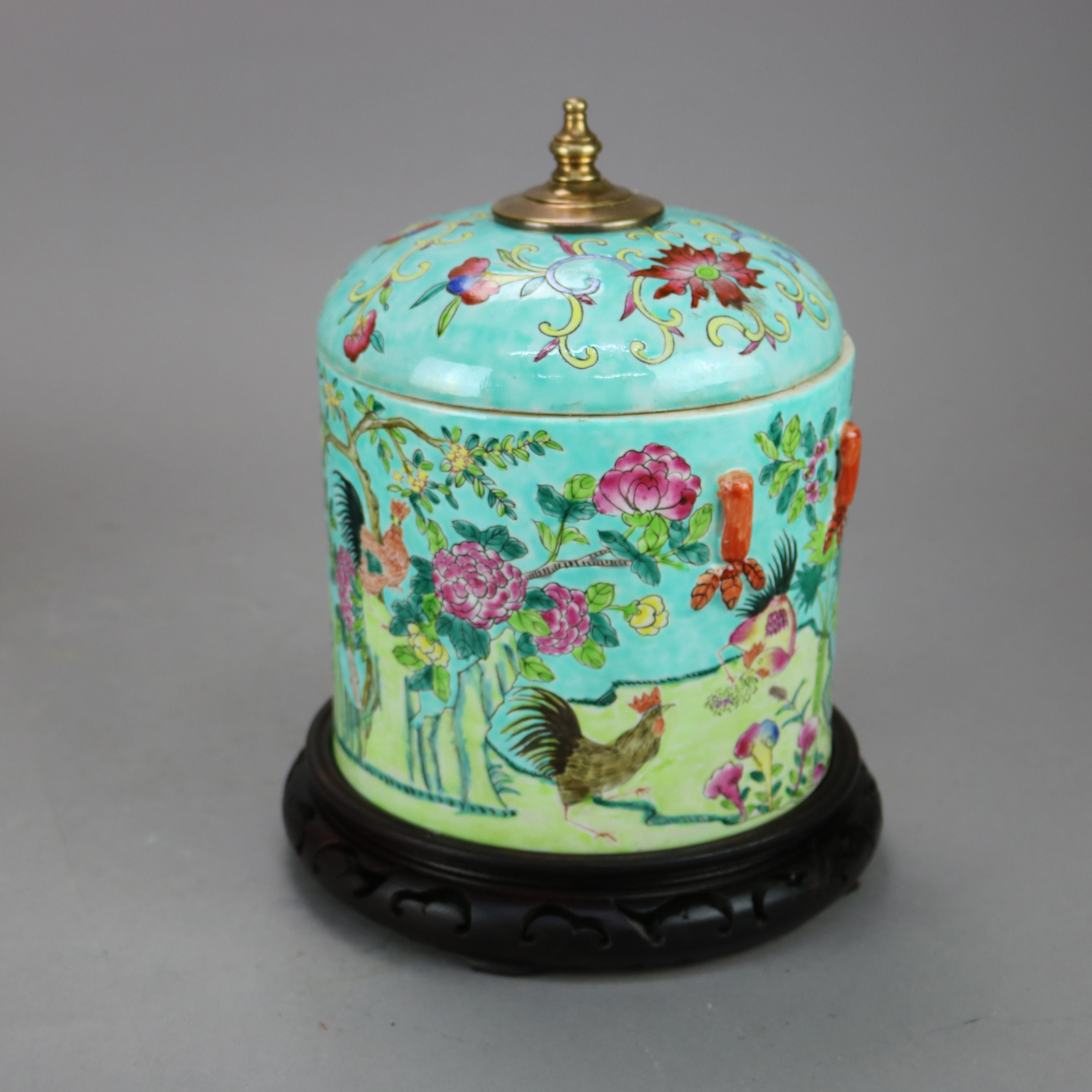 An antique Chinese porcelain covered jar offers hand painted garden motif with birds and flowers, flanking handles and is seated on carved hardwood stand, marked on base as photographed, c1930

Measures - 11.5''H x 8.25''W x 8.25''D; Jar 9.75'' x
