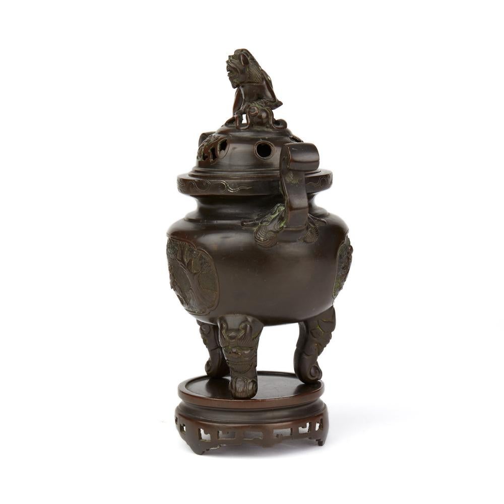 A very fine antique Chinese Qing twin handled bronze censer with cover and stand. The censer is very finely made standing raised on three mask and paw feet with the S scroll handles formed from tongues emerging from moulded heads. The body of the