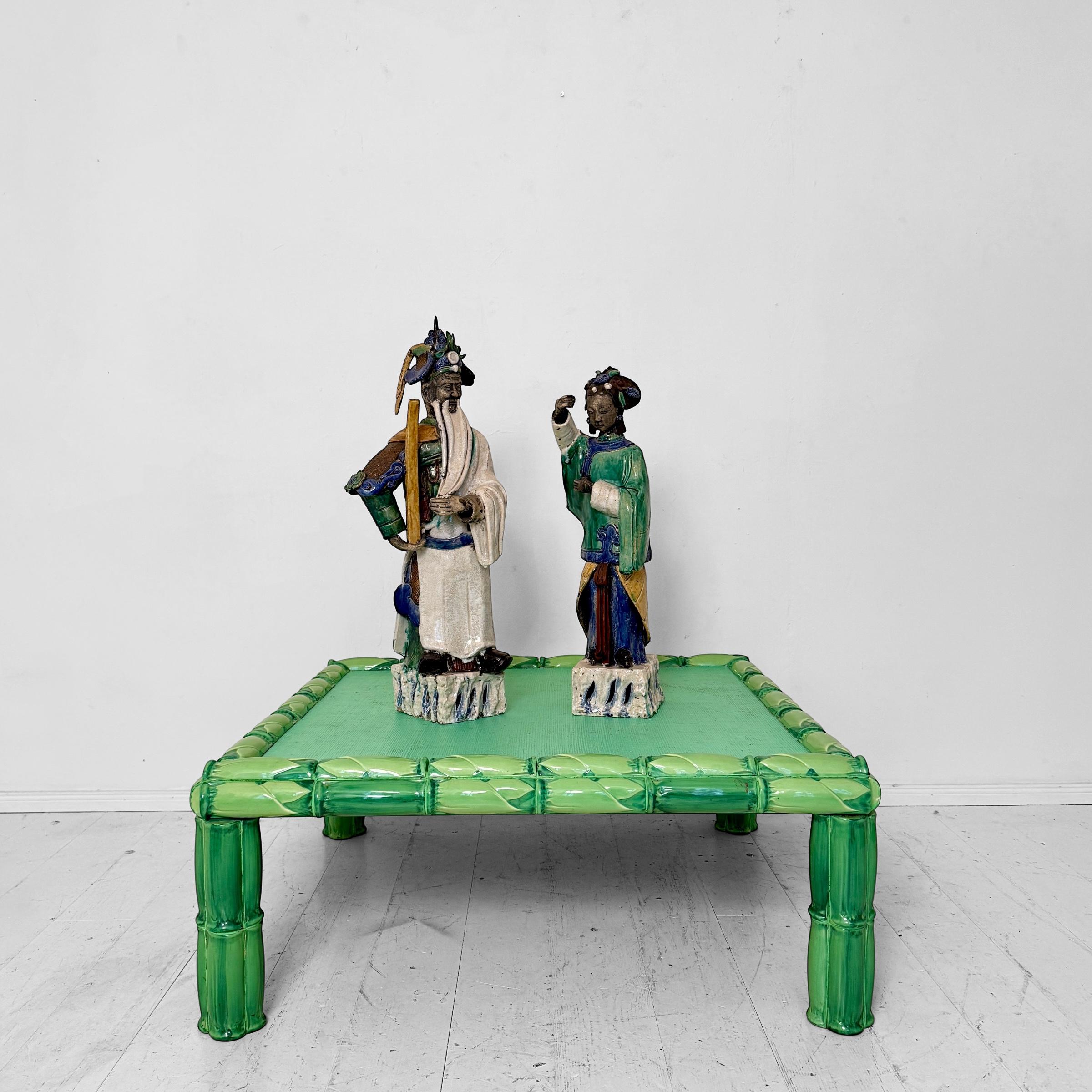A fine pair of Chinese ceramic sculptures from the Qing dynasty, dating to around 1880. These figures are richly detailed and hand-painted in a striking palette of green, blue, white, and ochre glazes. Each sculpture represents a courtly figure,