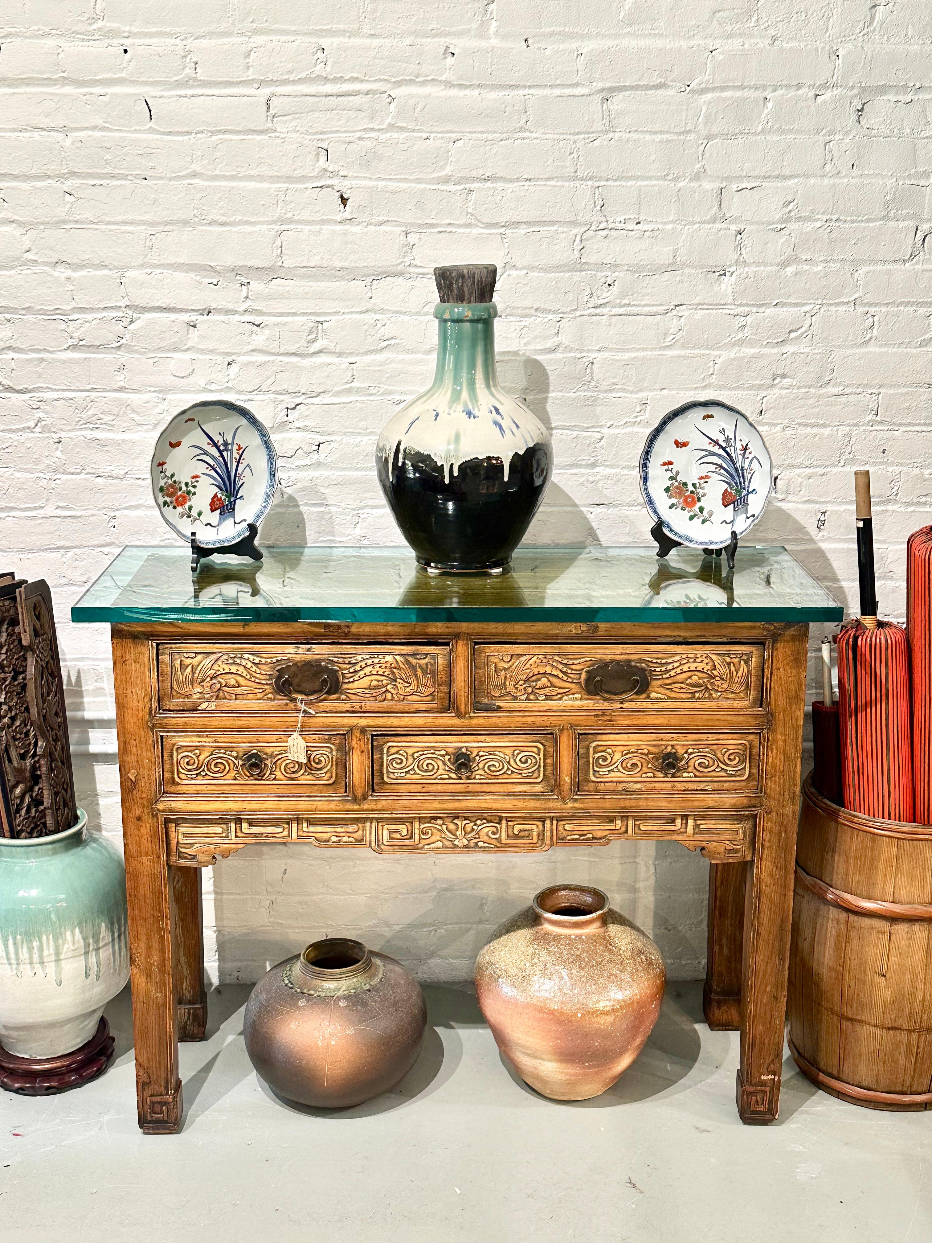 Disponible en la Galería Shogun's de Portland, Oregón, desde hace más de 40 años especializada en Arte y Antigüedades Asiáticas.

Se trata de una mesa auxiliar o consola china antigua del siglo XIX, de la dinastía Qing. Los cinco cajones están
