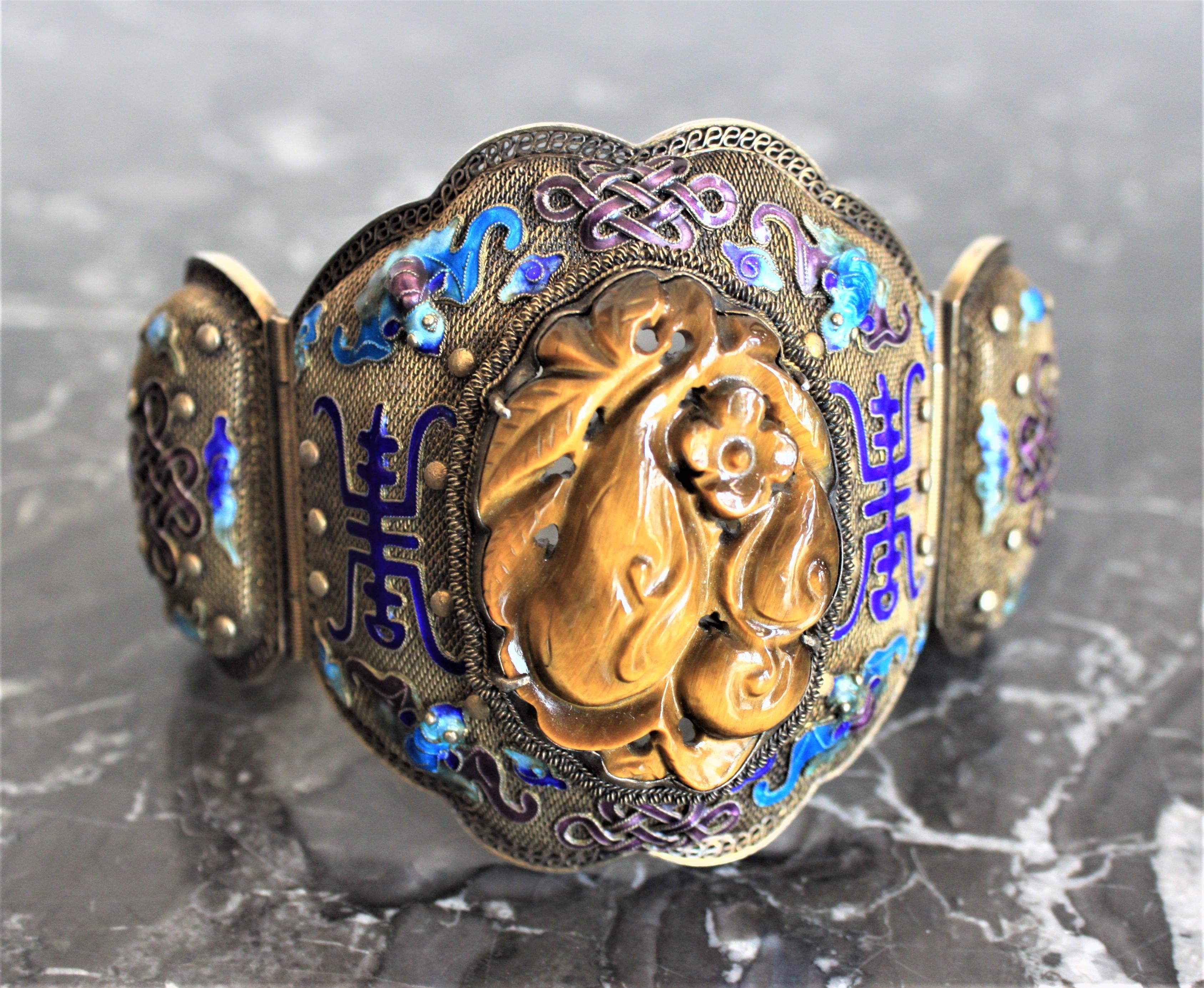 Dating from the late Qing Dynasty period, this very large and intricately constructed cuff bracelet is composed of three panels of a silver border completely filled in a very fine silver mesh with cobalt blue and turquoise enamel decoration. The