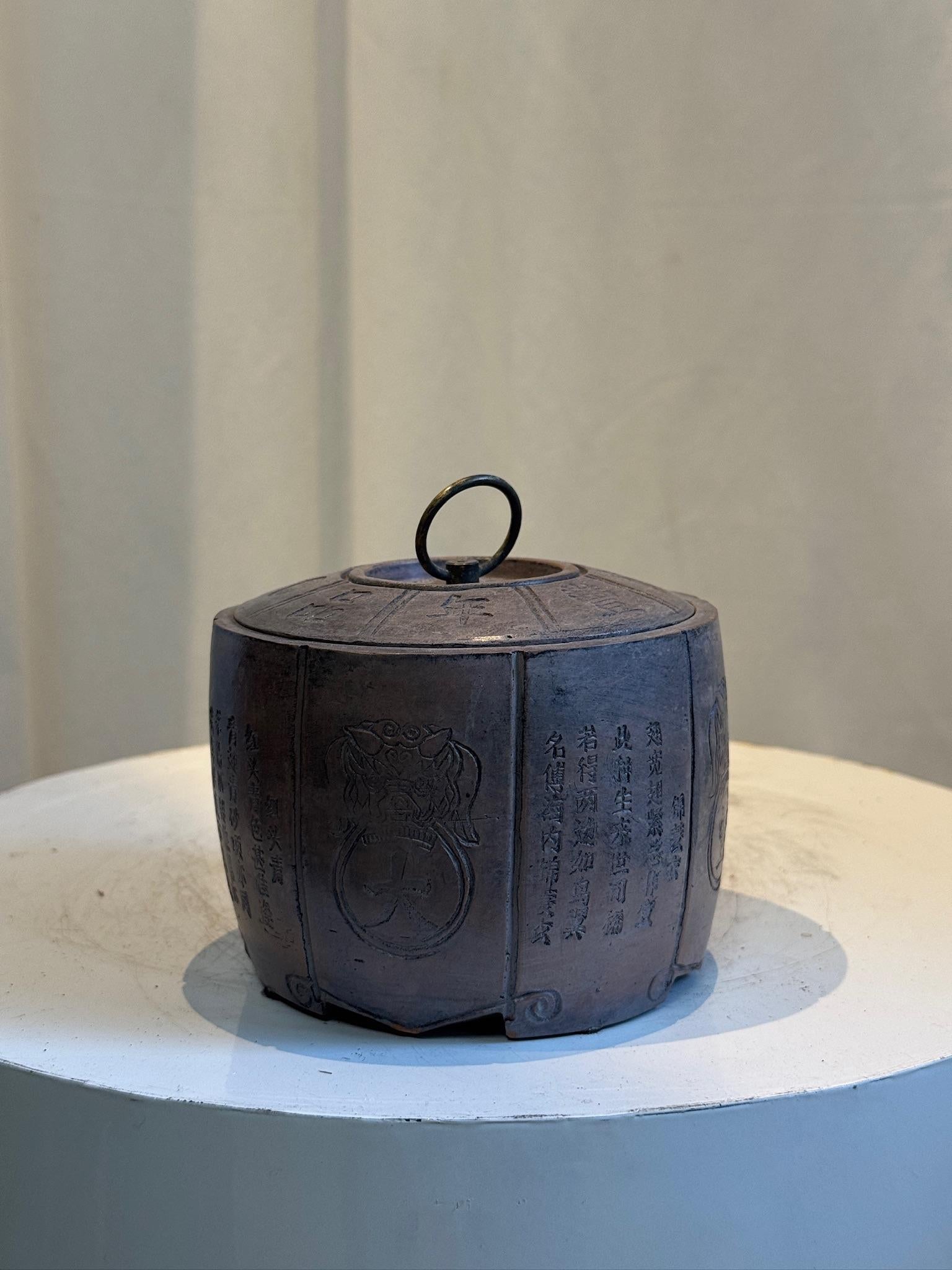 Se trata de una vasija antigua china con tapa, finamente elaborada, probablemente inspirada en el periodo de la dinastía Qing o datada en él. De forma octogonal, la jarra tiene una tapa desmontable con un asa de lazo en el centro y paneles