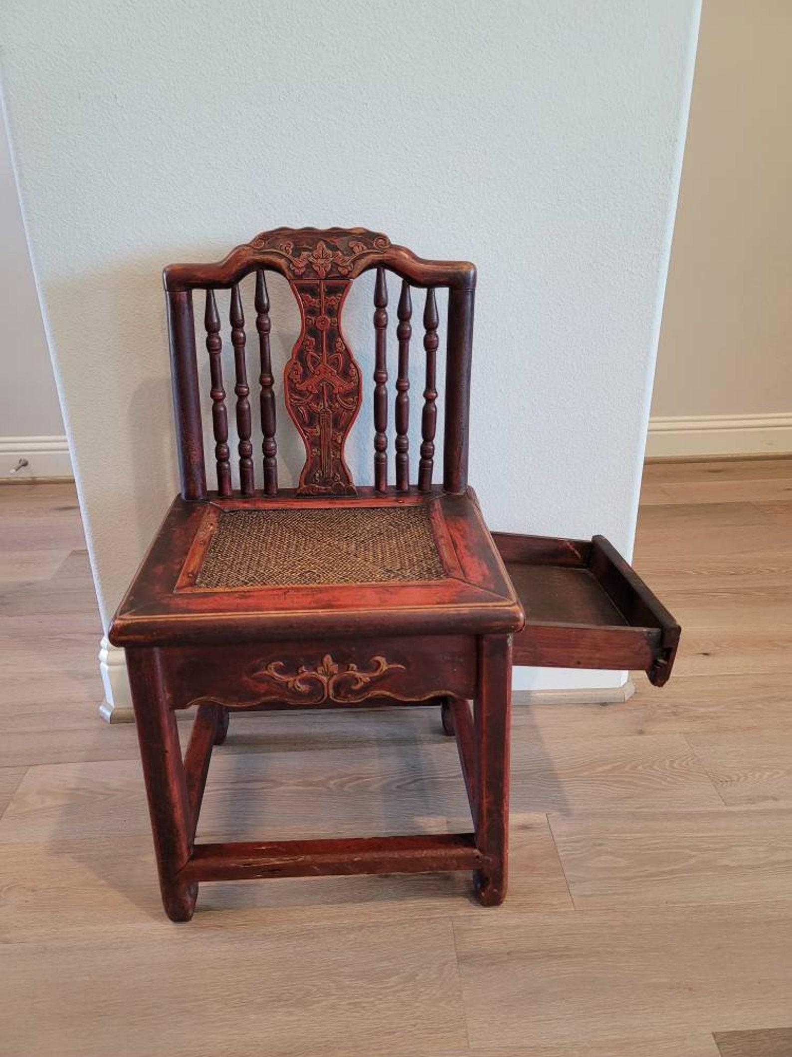 A Qing dynasty (1644–1912) Chinese ox blood red lacquered parcel gilt carved Hongmu wood wedding chair.

Unusual form featuring a concealed storage drawer and diminutive low chair size. 

Hand-crafted in China the 19th century, having a carved