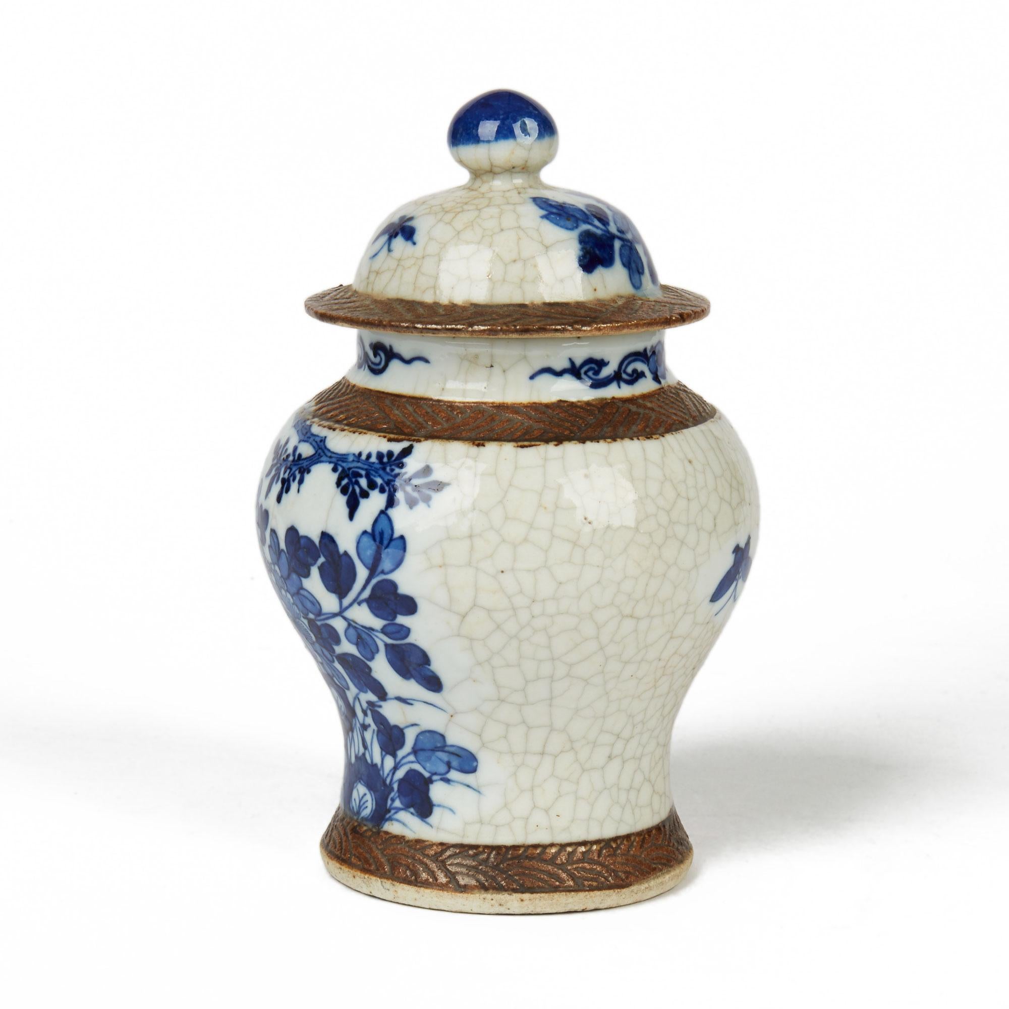 A very fine antique Chinese porcelain lidded ginger jar of rounded bulbous shape with hat shaped cover painted in blue and white with a tree and flowering shrubs on a cracquel ground and with matted brown patterned banding around the edges. The jar