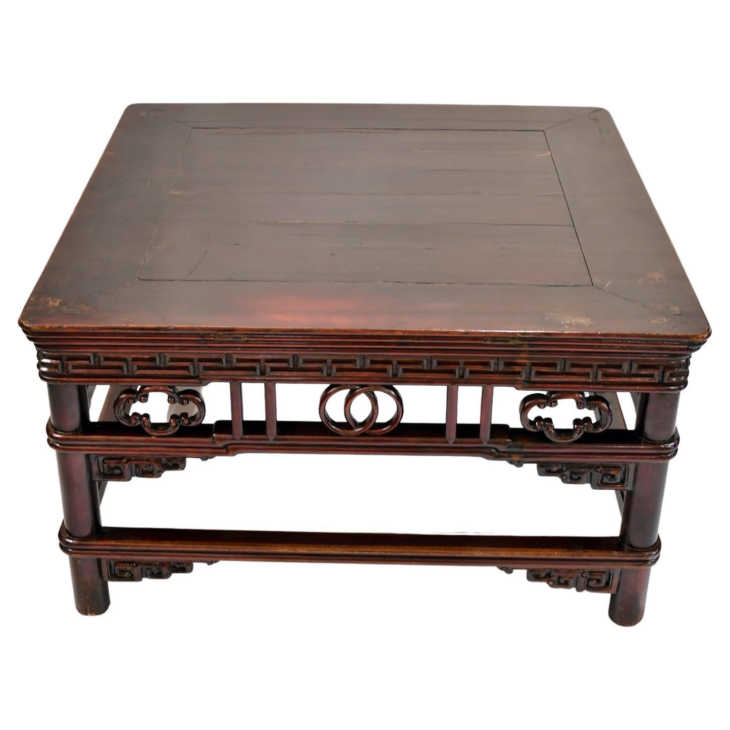 From the Shanxi province, a very beautiful Chinese Qing table that was lowered to function as a coffee table and offers a square top with double wrap-around stretchers & decorative braces. Made of hardwood & painted with a rich cinnabar-color paint.