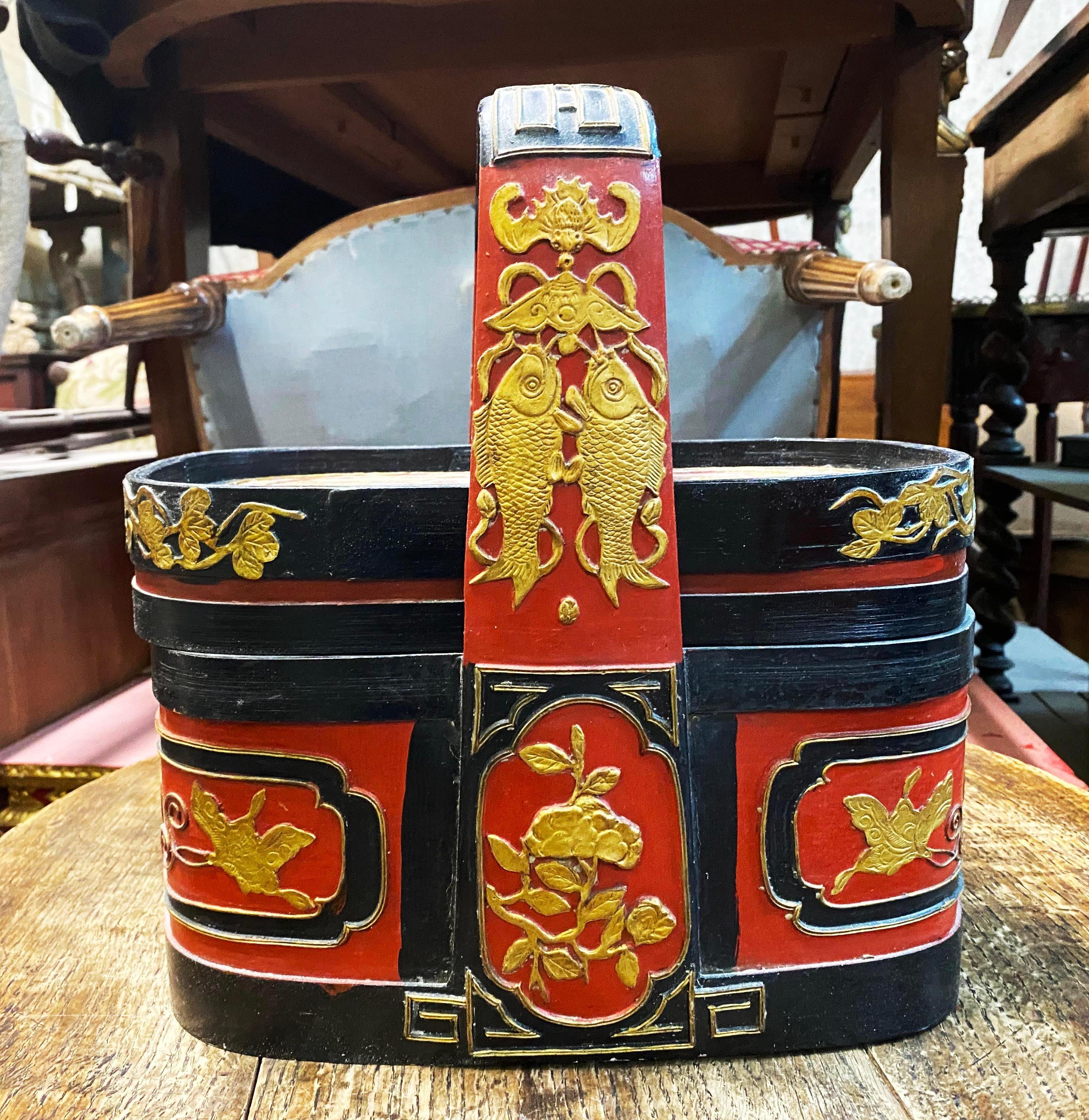 Antique Chinese Wooden Wedding Basket (c. 1860 - 1880) with red and black lacquer finish. So-called Peking opera basket. Top in gold leaf design depicts a Chinese sage on horseback with attendants. Pair of carp fish appear on the handles and peony