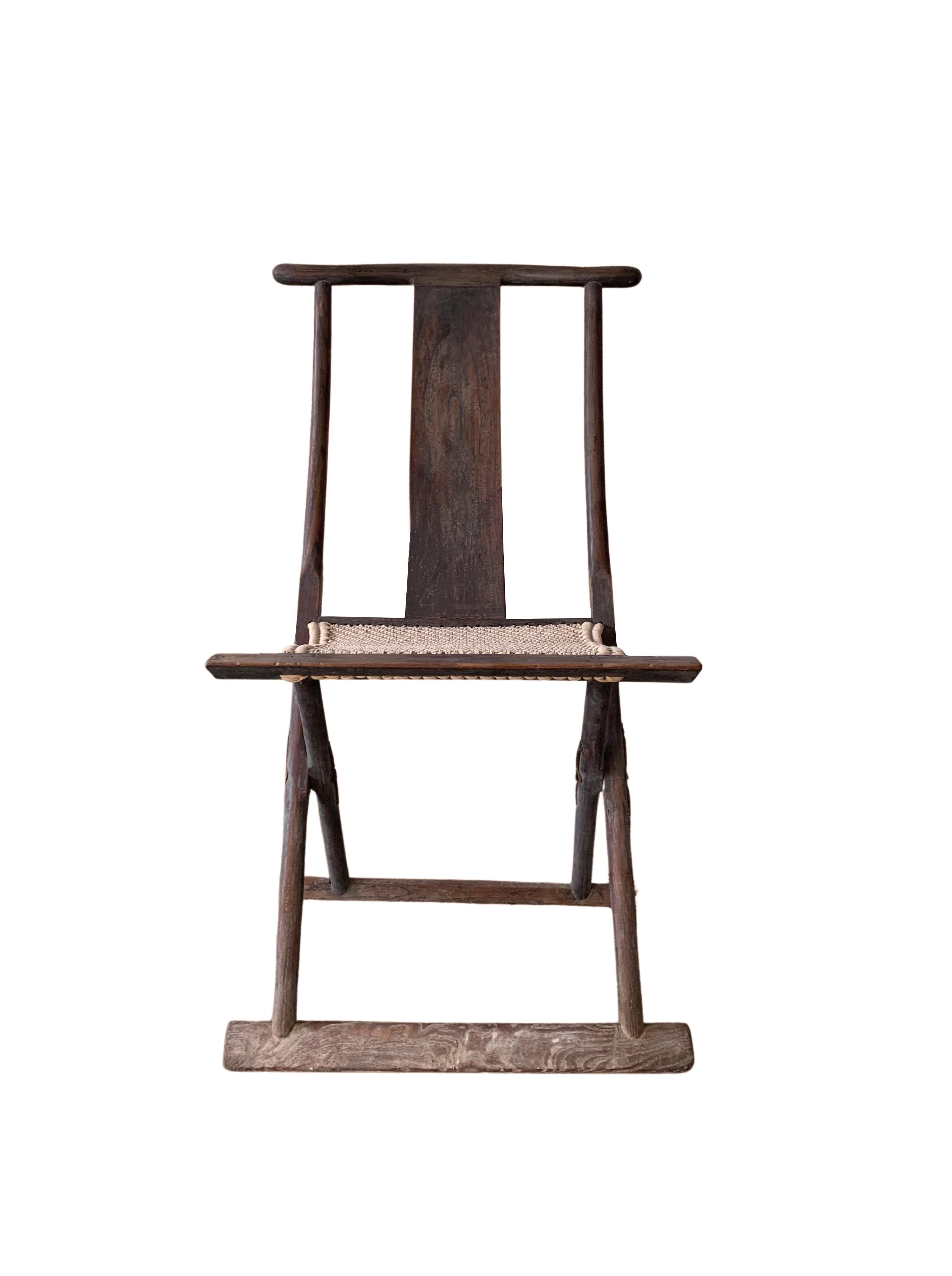 Dieser Klappstuhl aus dem frühen 20. Jahrhundert wurde einst von chinesischen Reisenden benutzt. Die Sitzfläche ist aus gewebtem Stoff gefertigt, der zusammen mit der Rückenlehne für einen bequemen Stuhl sorgt. Sein elegantes, schlankes und