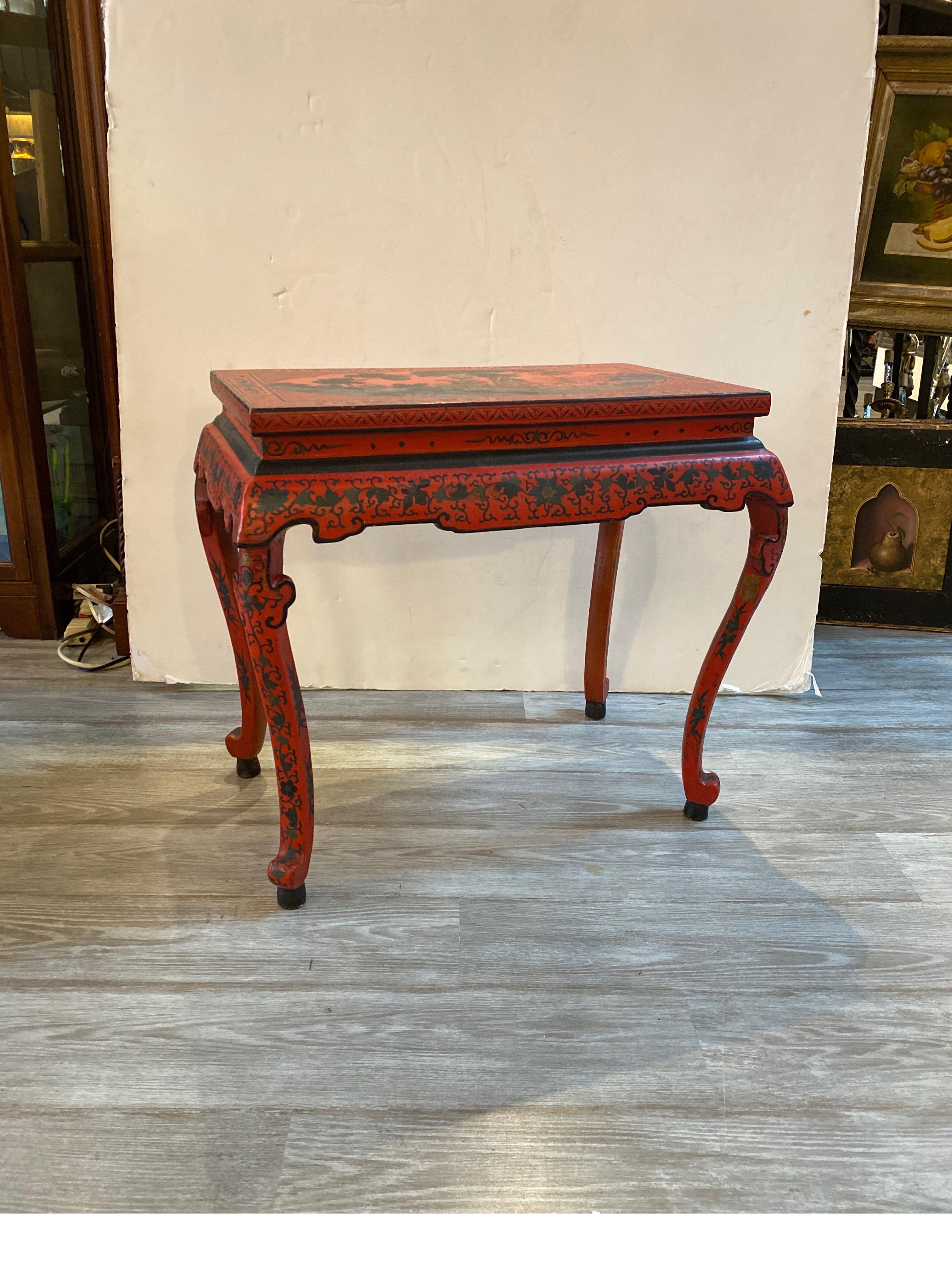A circa 1920 Chinese red lacquer low tea table with hand painted decoration. The table in very good original condition with slight wear on a few places. 24 inches tall.