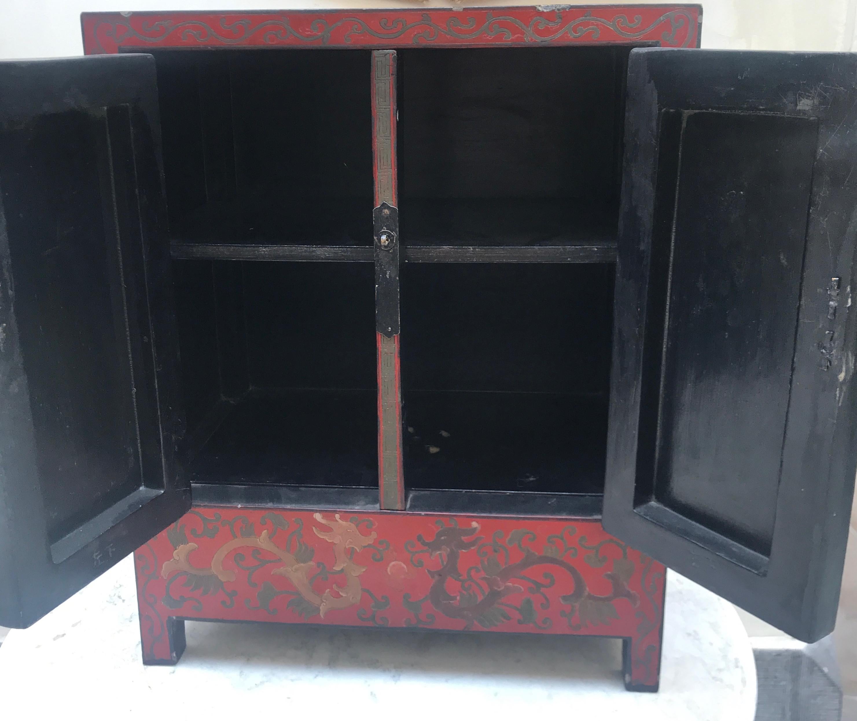 This red lacquer Chinese cabinet was made to set on a table, but could also be used today as a side table.
The incised work designs of five toed dragons frolicing in the seas and heavens are beautifully executed in lacquer colors of olive green,