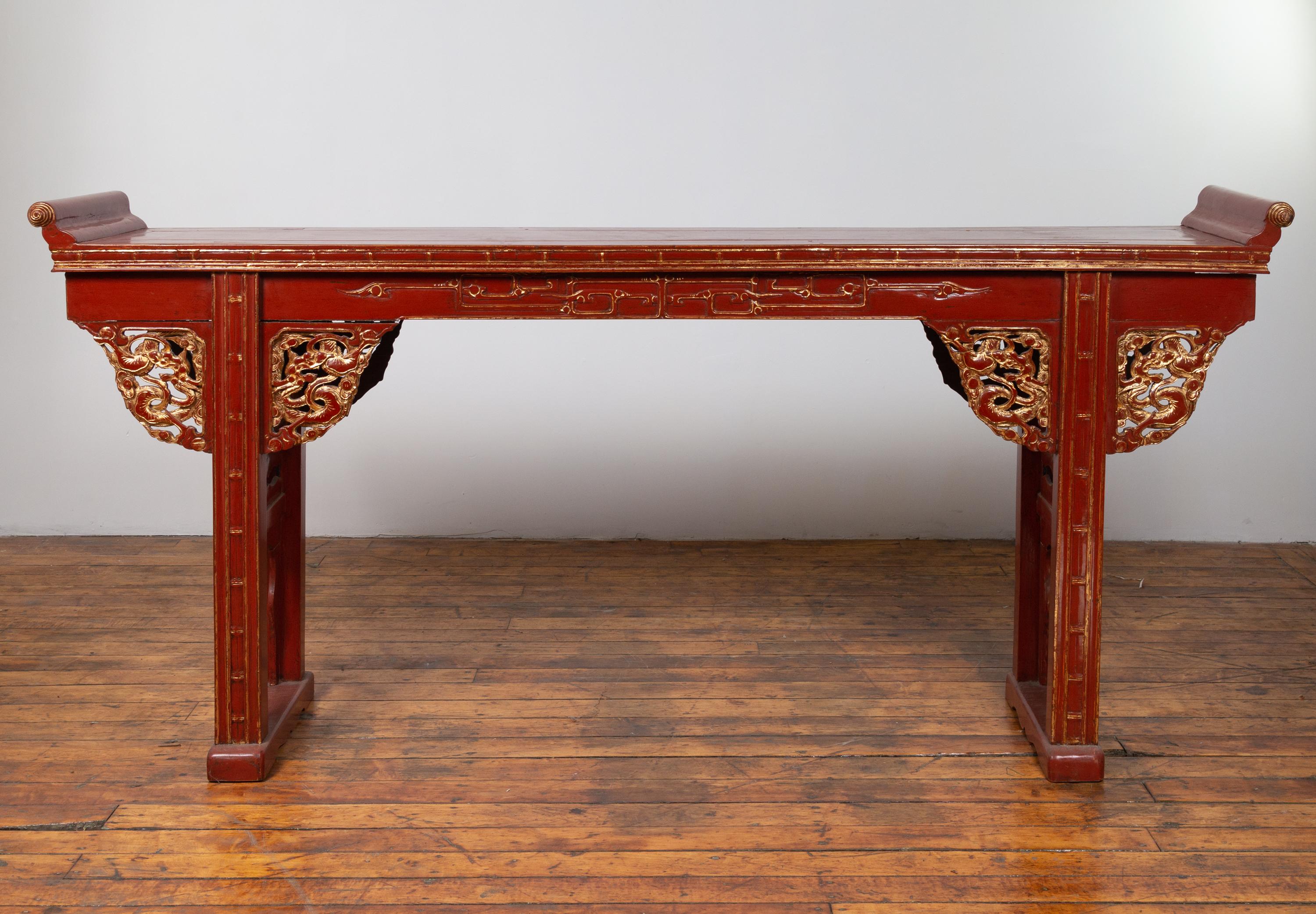 Ancienne table console d'autel chinoise du XIXe siècle, de style dynastie Ming, laquée en rouge, avec des rebords évasés, un tablier sculpté et des accents dorés. Née en Chine au cours du XIXe siècle, cette exquise table console autel présente un