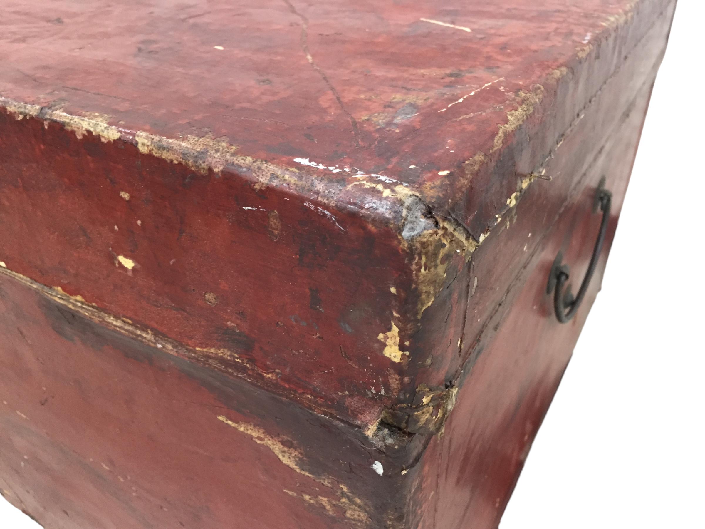 Antique Chinese red lacquered leather trunk mounted on a custom iron base. Trunk show evidence of were and there is color loss.