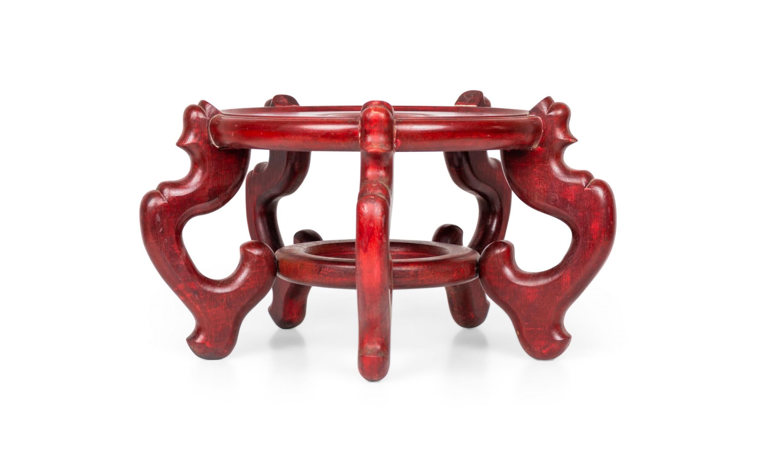 Antigua base / soporte chino de madera tallada y pintada de rojo para macetas, con una superficie circular para sostener una maceta o jarrón, que descansa sobre cuatro pies arqueados y tallados con una camilla circular.