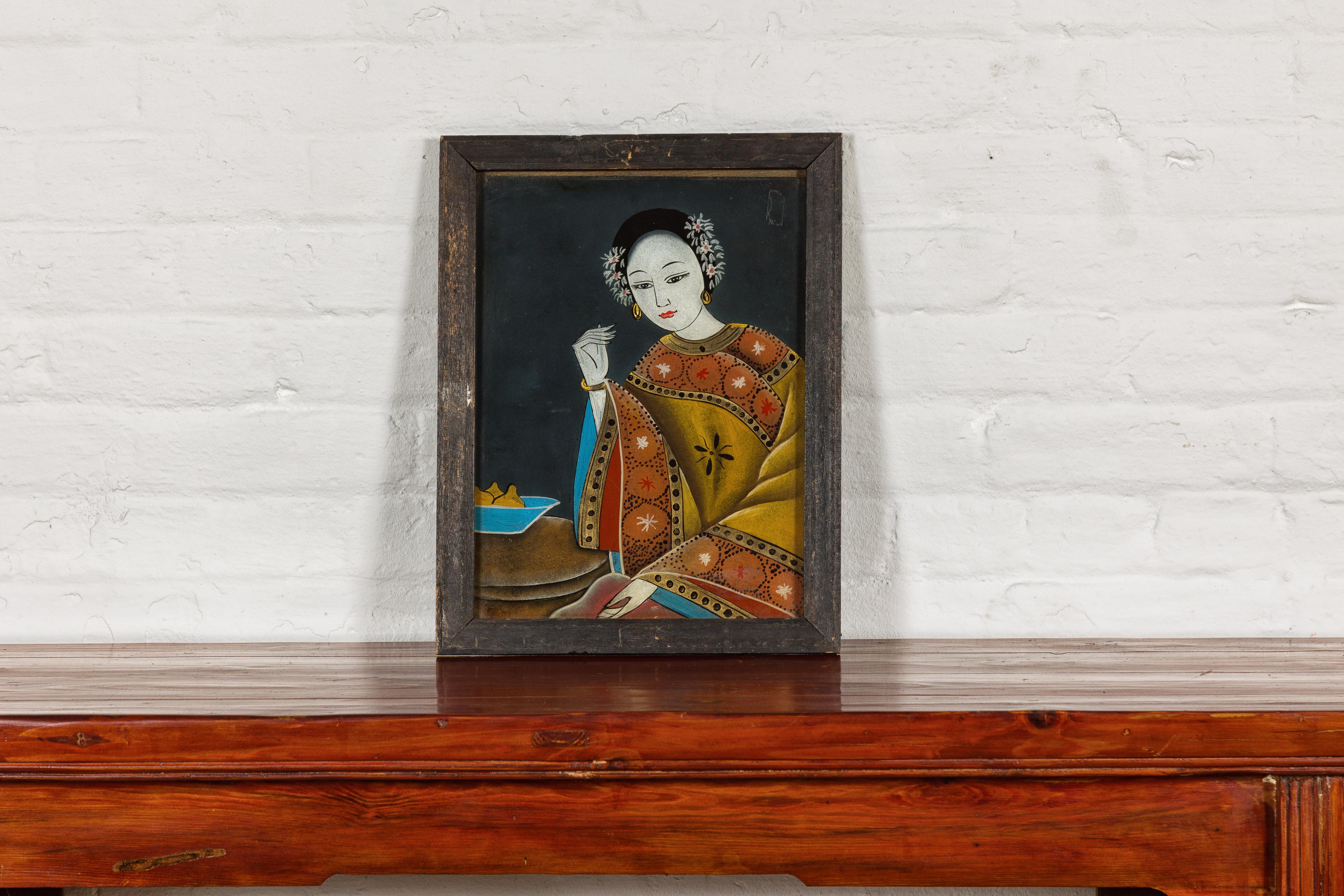 An antique Chinese reverse painting on glass from the early 20th century depicting a woman sitting next to a bowl of fruits. This exquisite early 20th-century Chinese reverse painting on glass captures a serene and contemplative moment, depicting a