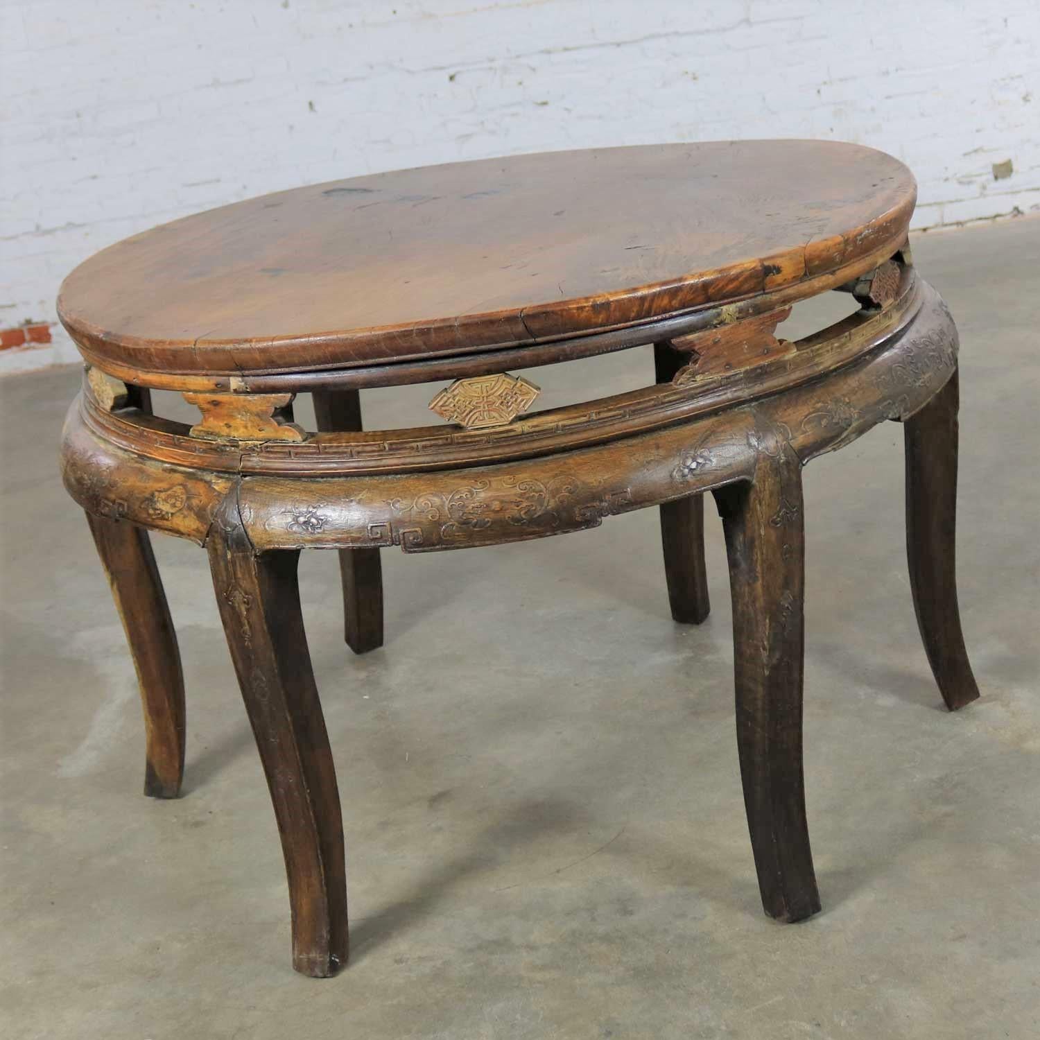Handsome antique Chinese round and hand carved center table of elm wood. This table is in good antique condition with lots and lots of gorgeous age patina including patched spots, uneven surfaces, warping, nicks and dings. We consider these things