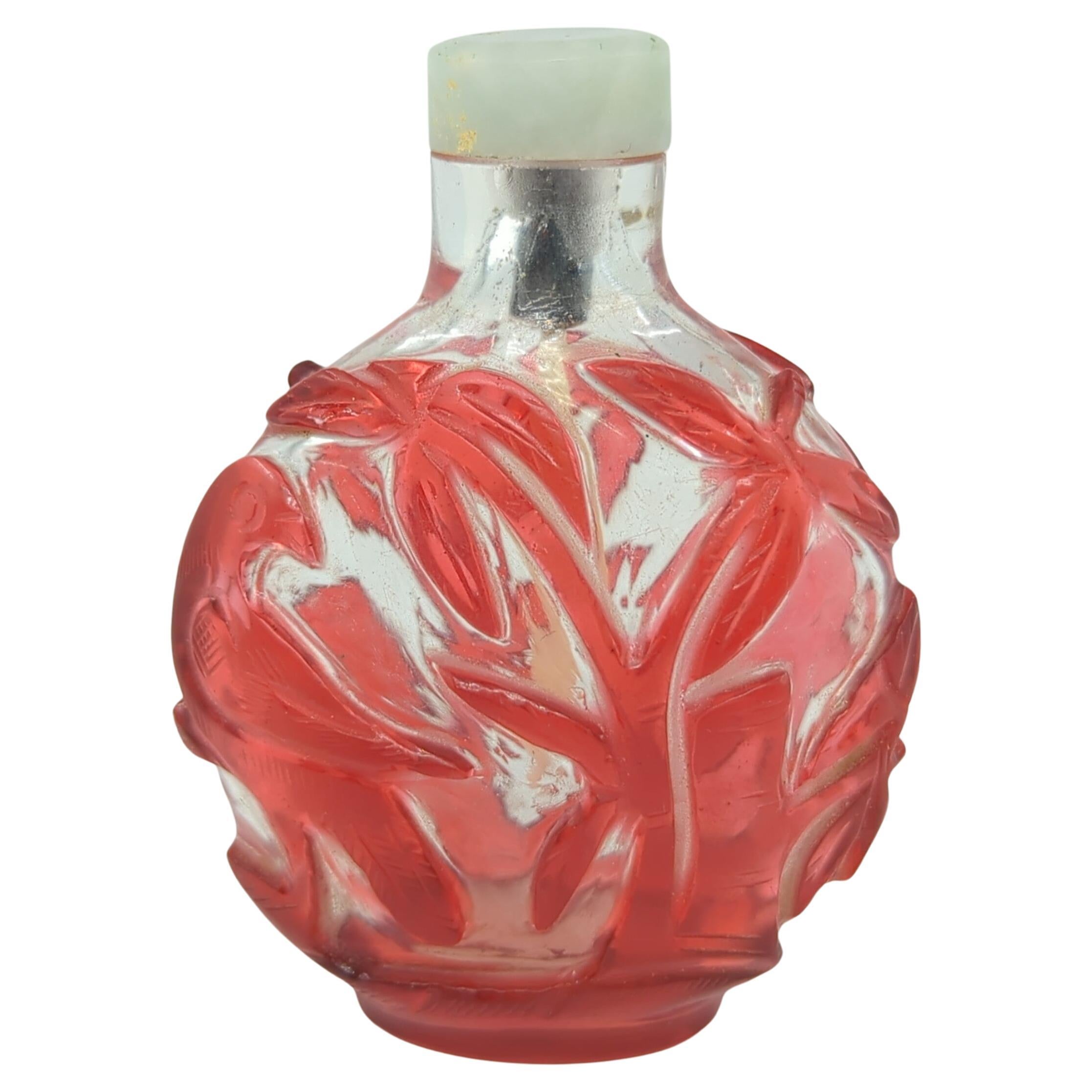 This late Qing to early Republic period snuff bottle is a fine example of ruby red glass overlay on clear glass ground, showcasing the esteemed glasswork techniques of the era. The bottle is in a compressed globular form, a shape that is both