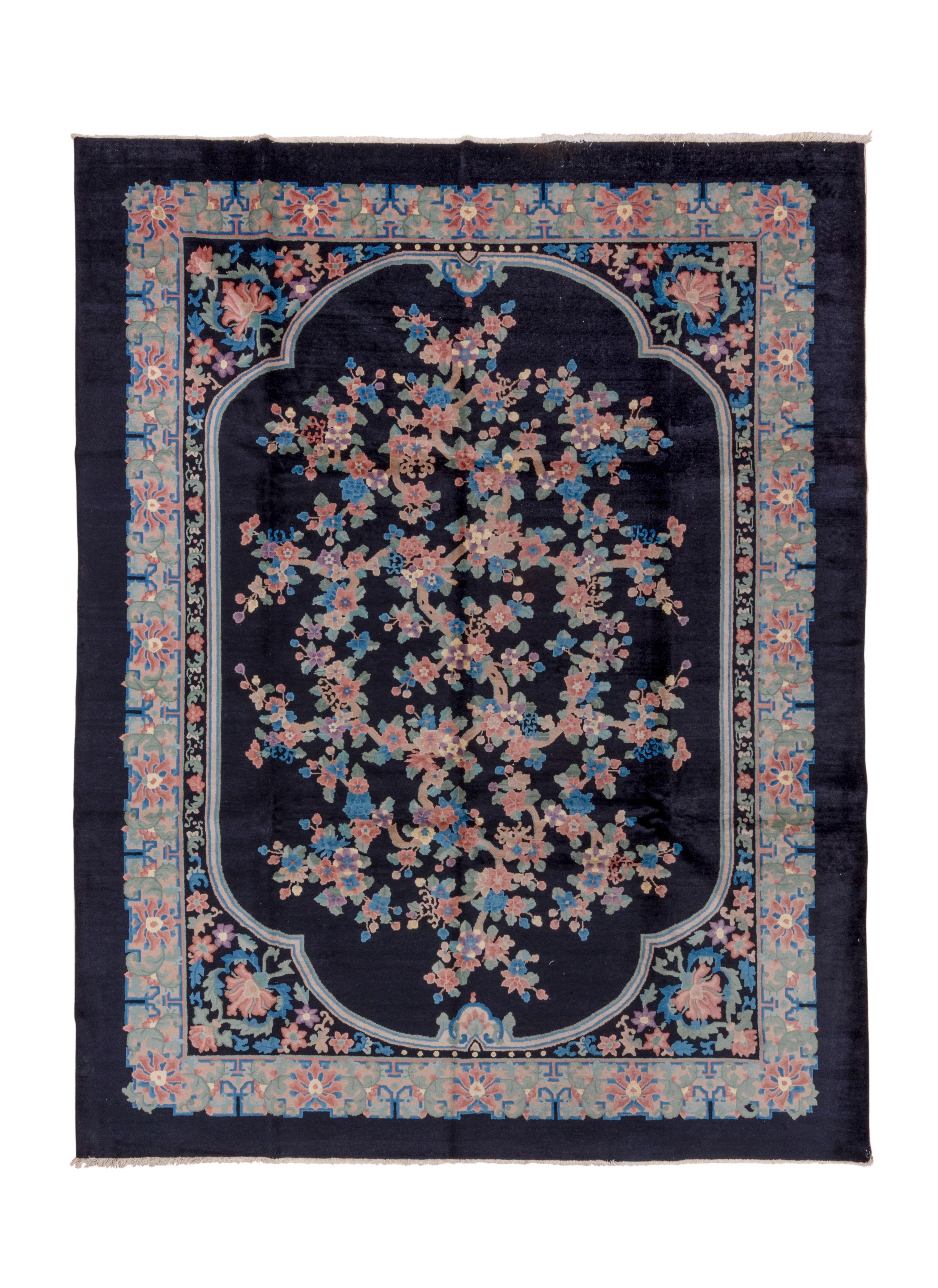 The shaped charcoal sub-field displays a complex flower, leaf and stem rootless creation, within corners with semi-peonies and flower trails alongside the sub-field. Cerulean blue border of peonies embedded in stylized foliage. Plain charcoal outer