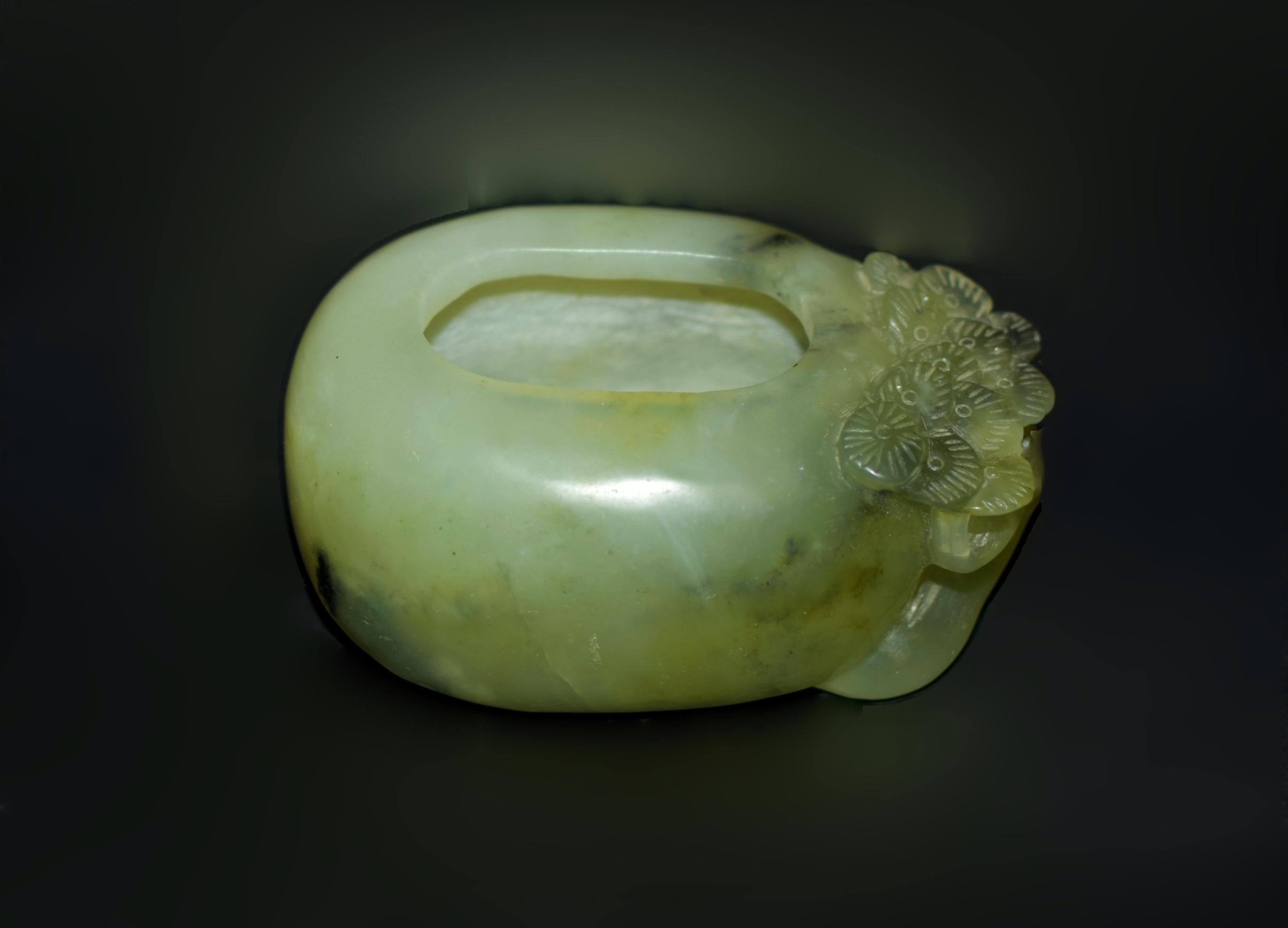 This beautiful, one-of-a-kind bowl is carved from a single piece of green gemstone serpentine. Its oval form features a deeply carved interior, with one end adorned by a finely carved pine tree. The robust trunk and verdant needles of this evergreen