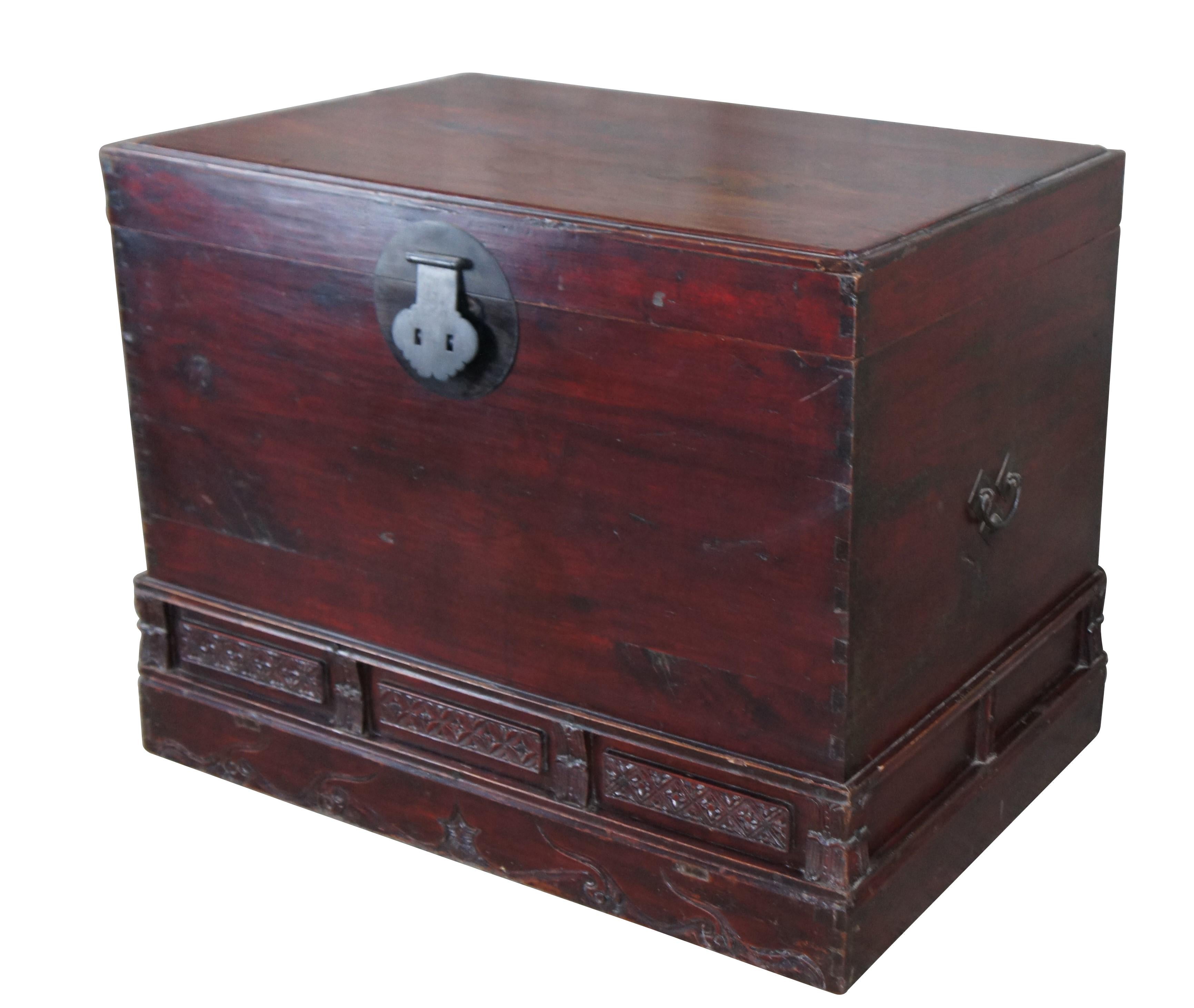 Late Qing Dynasty Red Lacquered Elm Trunk.  Made in Shandong East China, late 19th century.  Feature a rectangular body with dovetail construction at the corners and lower carved relief.  The trunk has traditional moon hardware at the center,