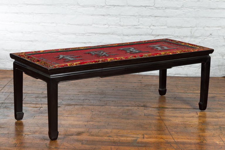 A Chinese antique shop sign with gold and red décor, turned into a coffee table with black horse hoof legs. Created in China, this coffee table captures our immediate attention with its striking red textured ground highlighting black calligraphy,