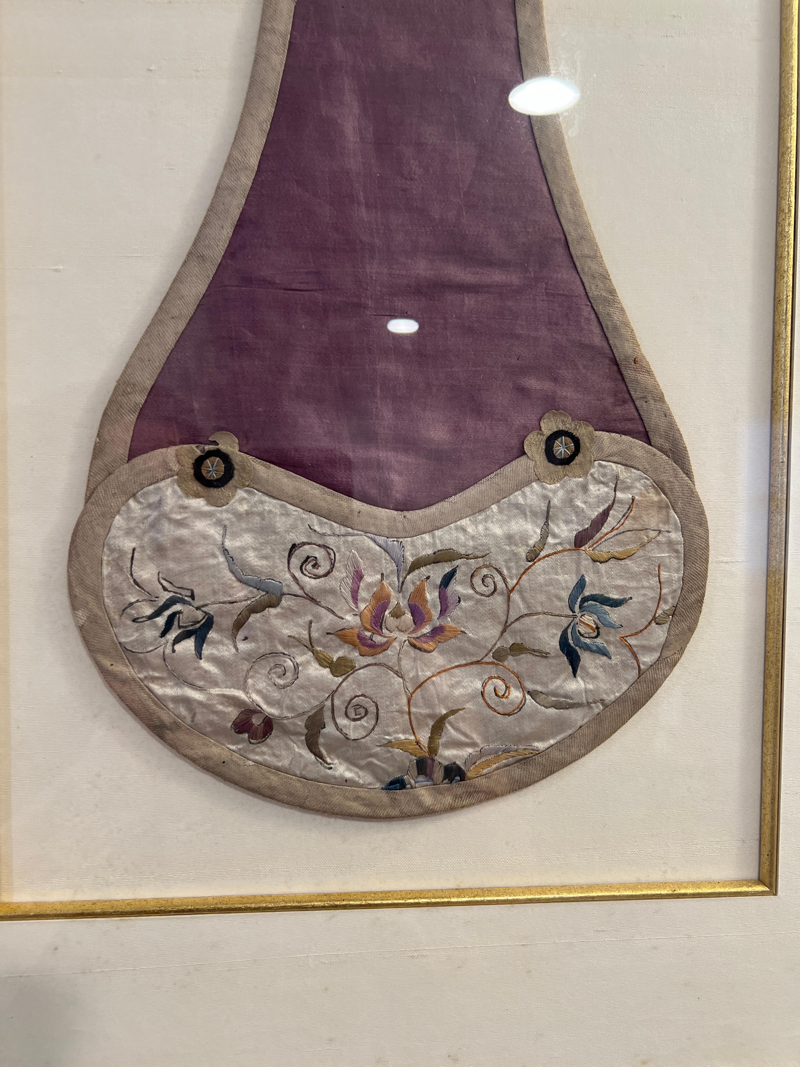 Chinese Qing Dynasty (1644-1911), 19th century. 

Step into the lavish world of the Qing Dynasty with this exquisite antique Chinese Silk Embroidery Child's Bib. Embellished with a foliate motif and scholar motifs stitched into the trim, this panel