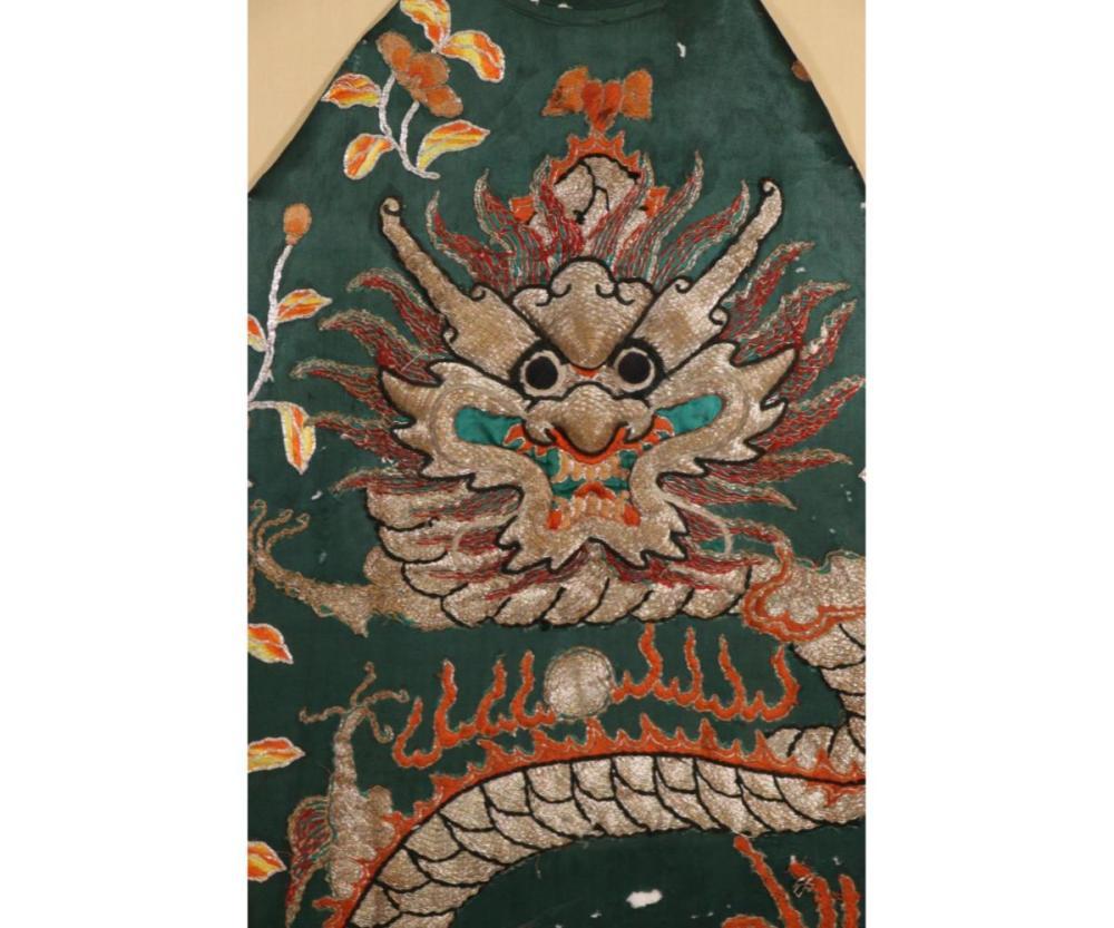 This exquisite antique Chinese silk robe fragment showcases a stunning blend of intricate artistry and cultural symbolism. The piece features a majestic dragon and a loyal dog intricately woven into the fabric, symbolizing power, strength, and