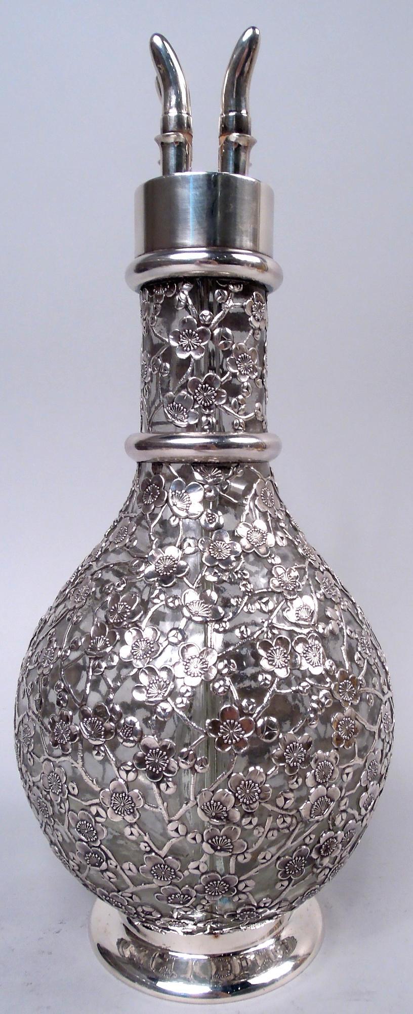 Chinese silver-mounted glass decanter, ca 1900. Ovoid bowl and cylindrical neck; interior partitioned forming four compartments. Blossoming branch cage. Neck rings and collar with flat top and four cork-mounted plugs. Raised foot. Glass is clear. A
