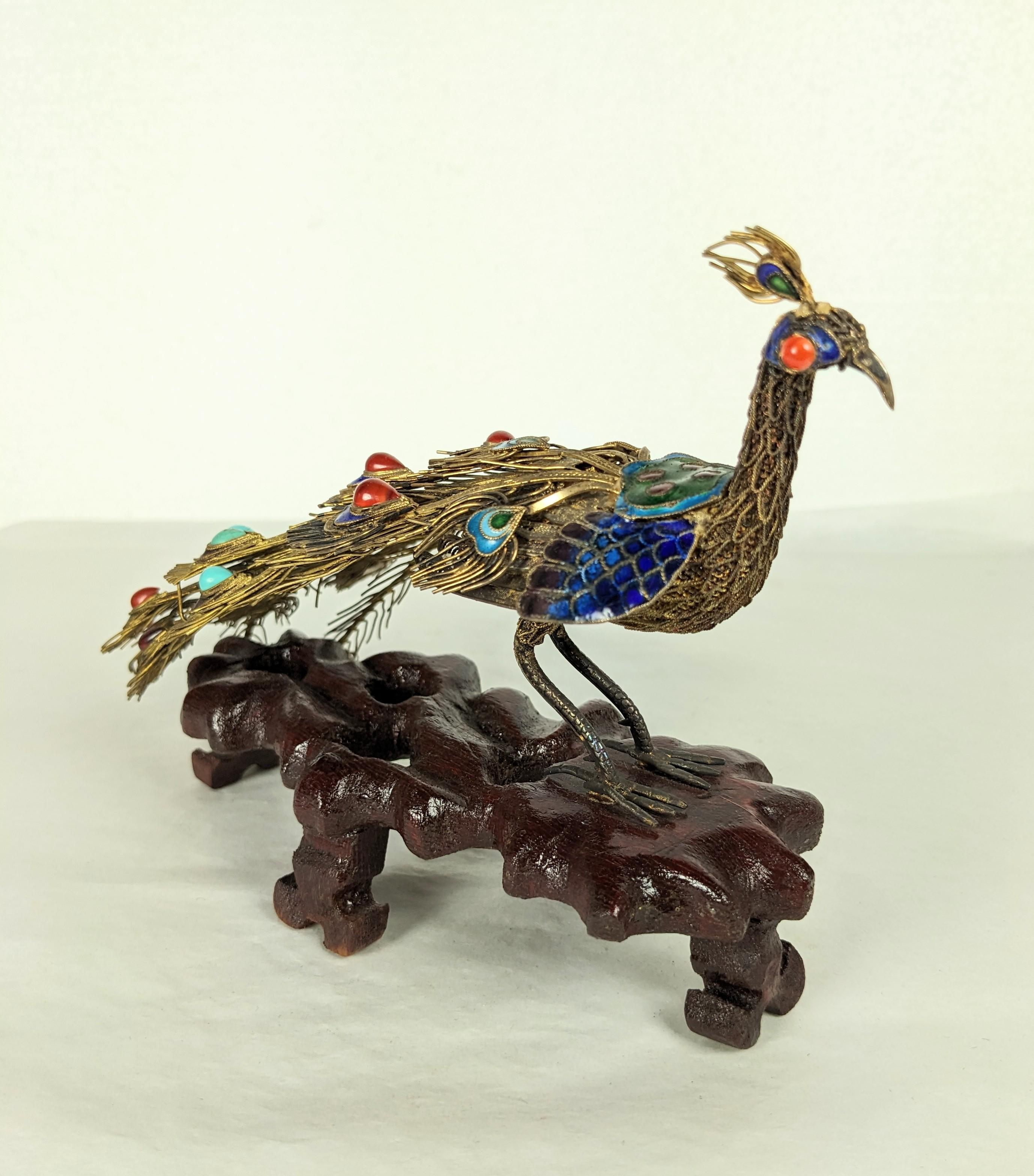 Antique Chinese Silver Gilt and Enamel Peacock from the 1940's on hand carved wood stand. Delicately constructed of vermeil sterling with colorful cloisonne enamel accents. Highlighted with semiprecious coral, turquoise and carnelian stones. 7